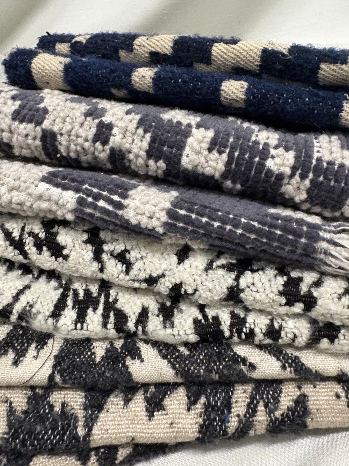Close-up of a collection of fluffy heavyweight fabric with various patterns in white, blue, and black 