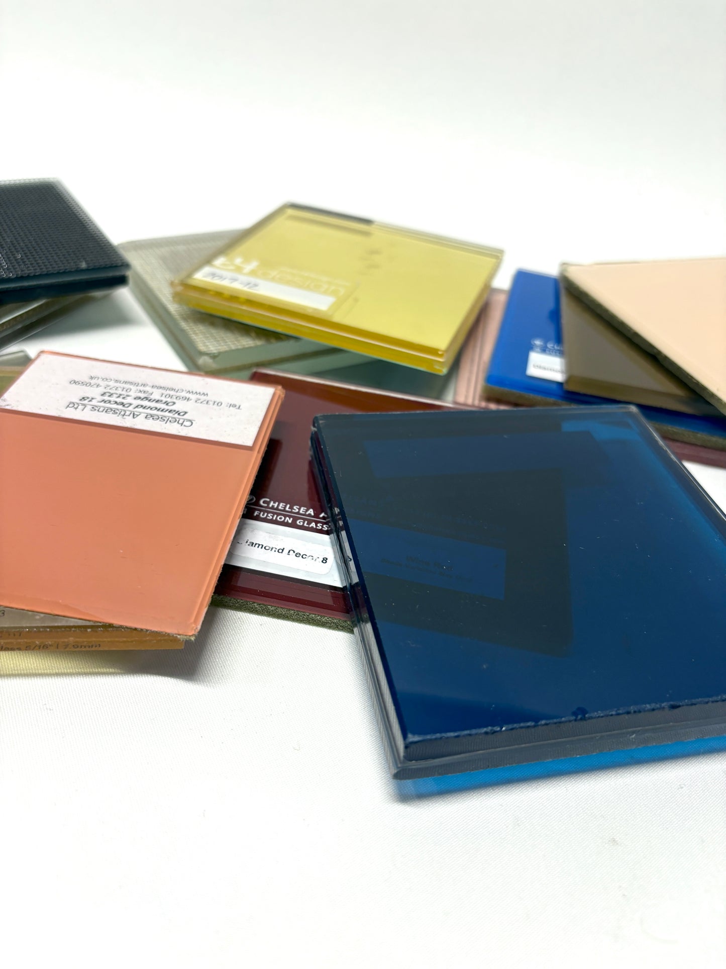 Collection of square colourful glass samples, some pieces are transparent