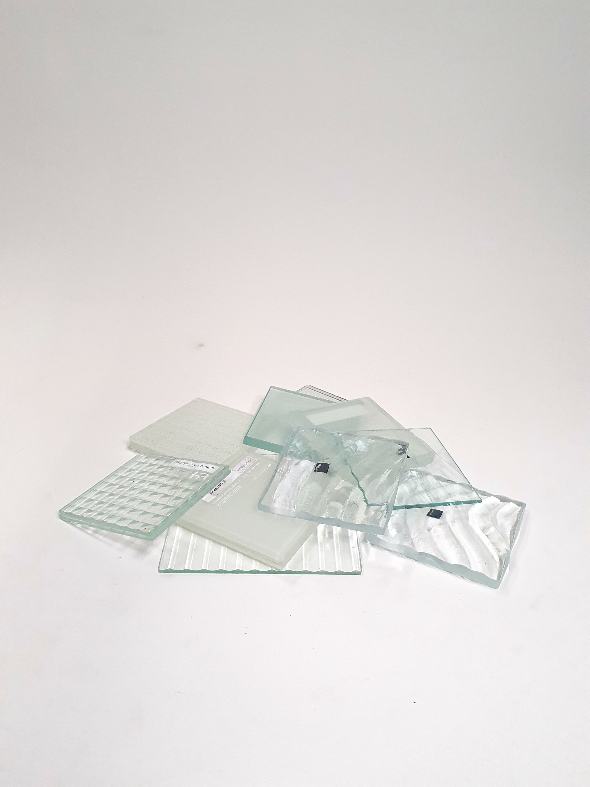 Pile of square transparent glass samples with various patterns 
