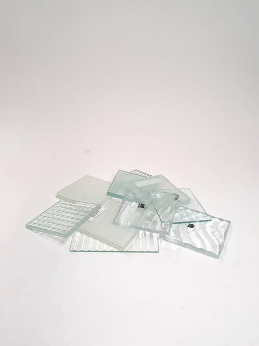 Pile of square transparent glass samples with various patterns 
