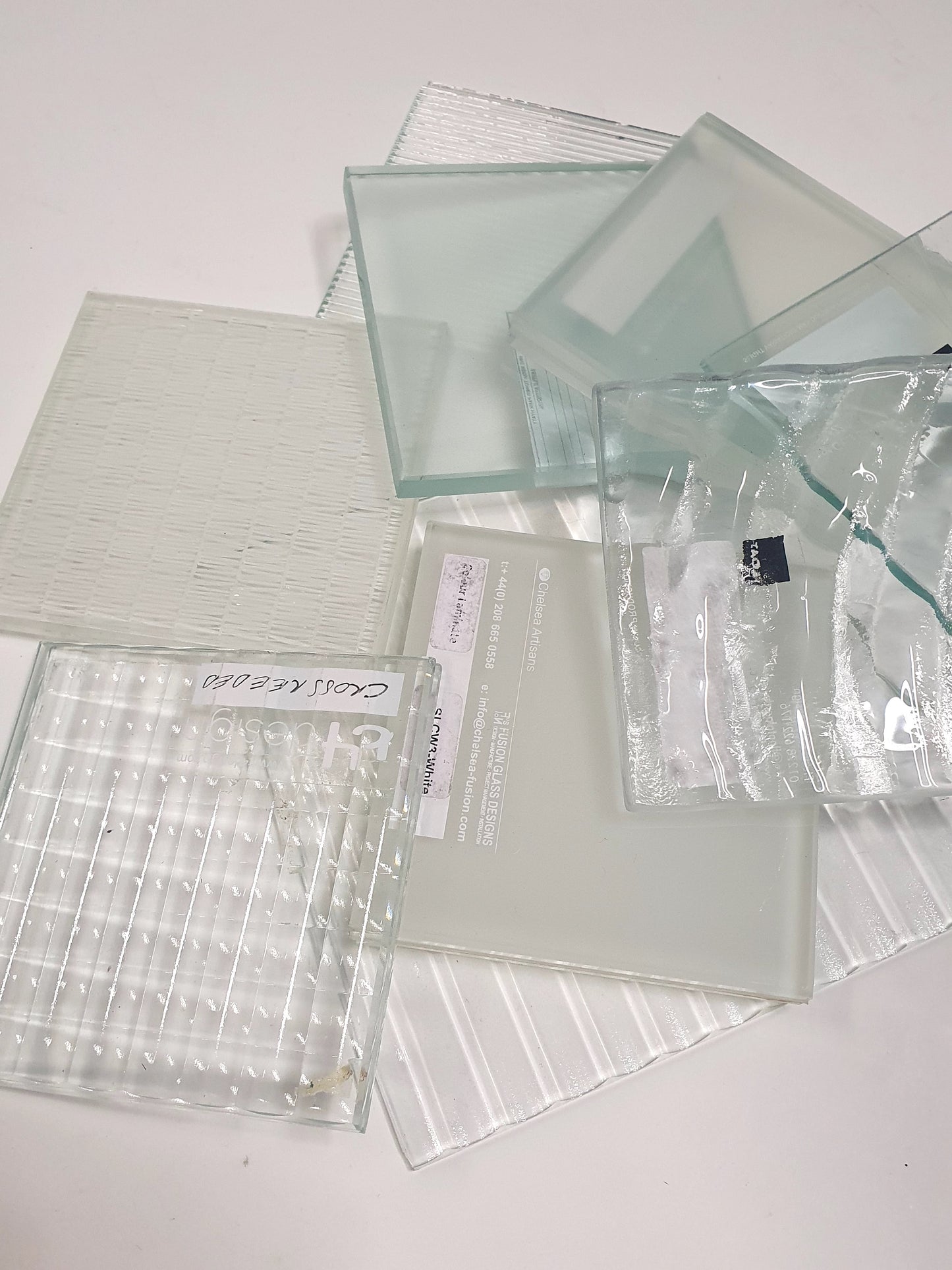 Pile of square transparent glass samples with various patterns 