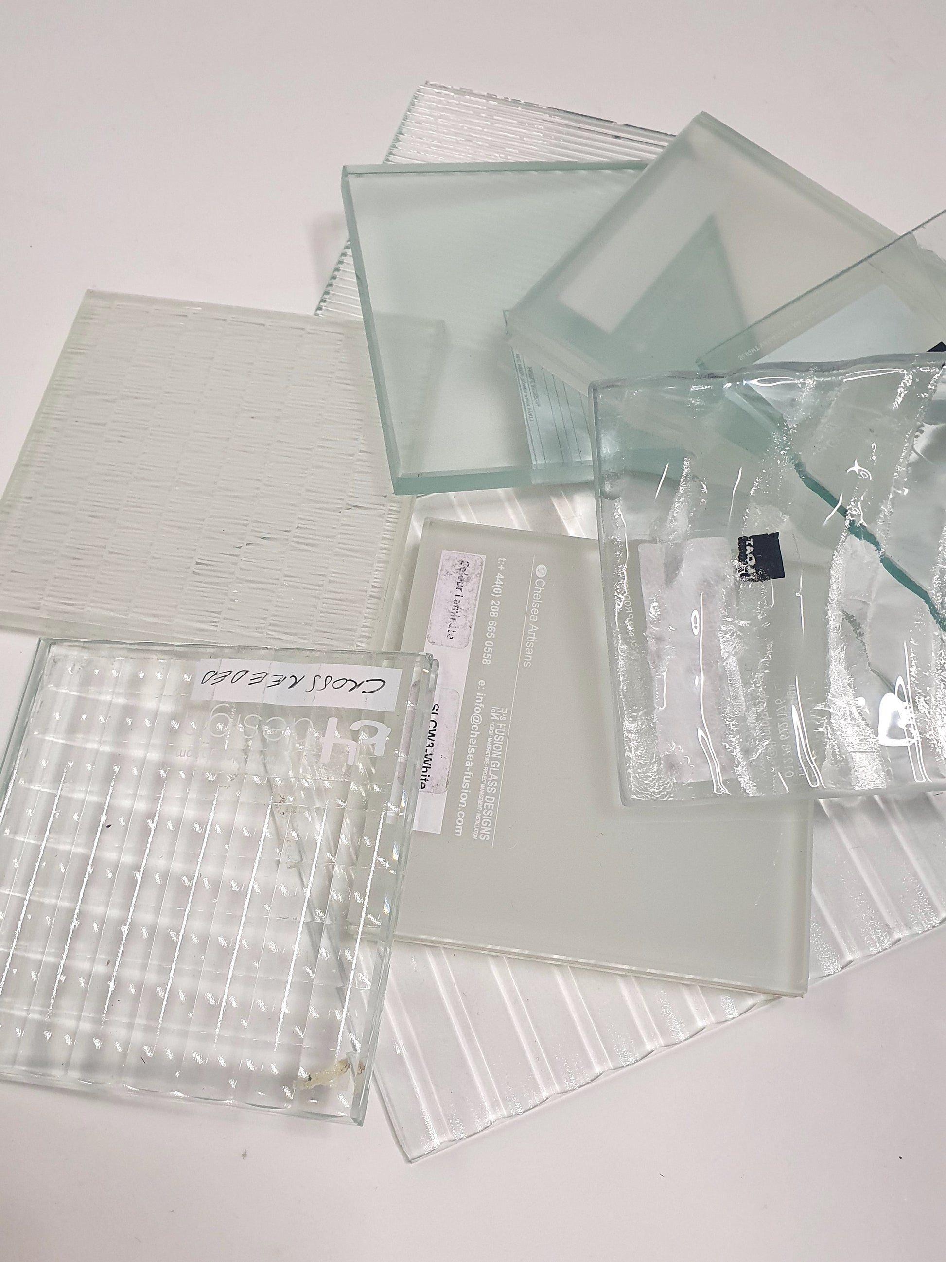 Pile of square transparent glass samples with various patterns 