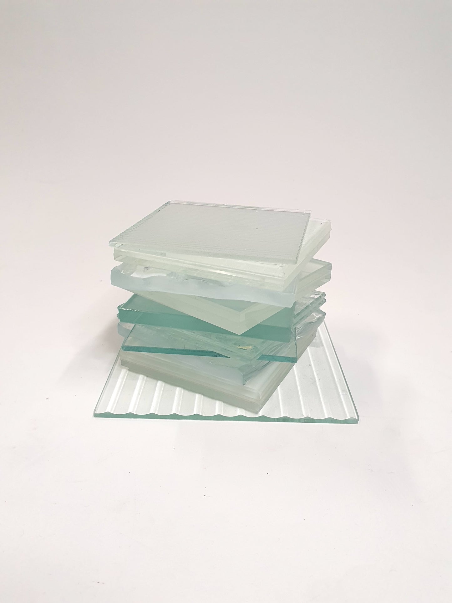 Pile of square transparent glass samples with various patterns 