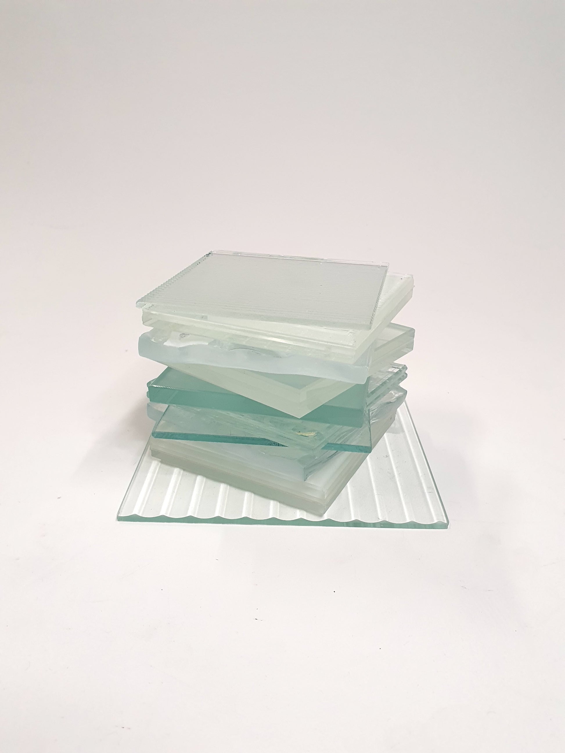 Pile of square transparent glass samples with various patterns 
