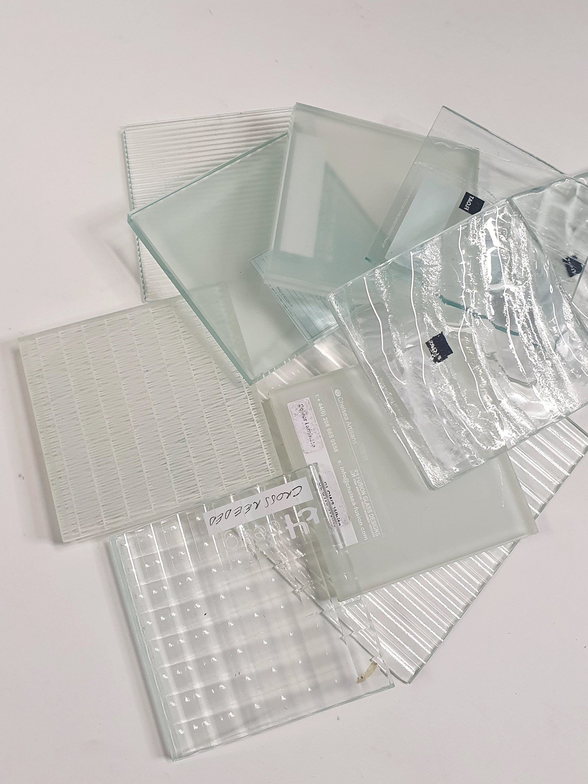 Pile of square transparent glass samples with various patterns 