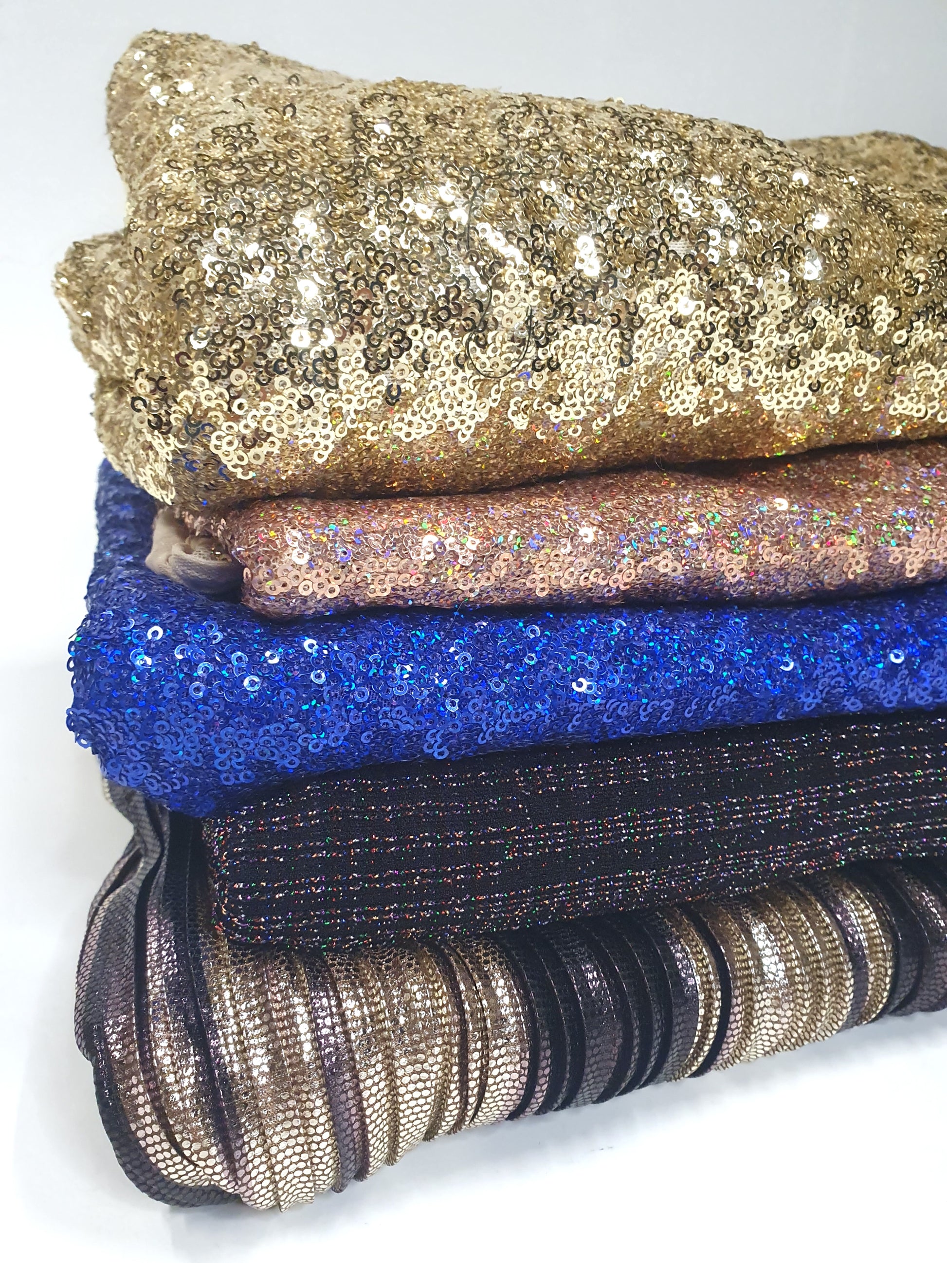 Pile of folded glitter fabric with gold, pink, blue, and black
