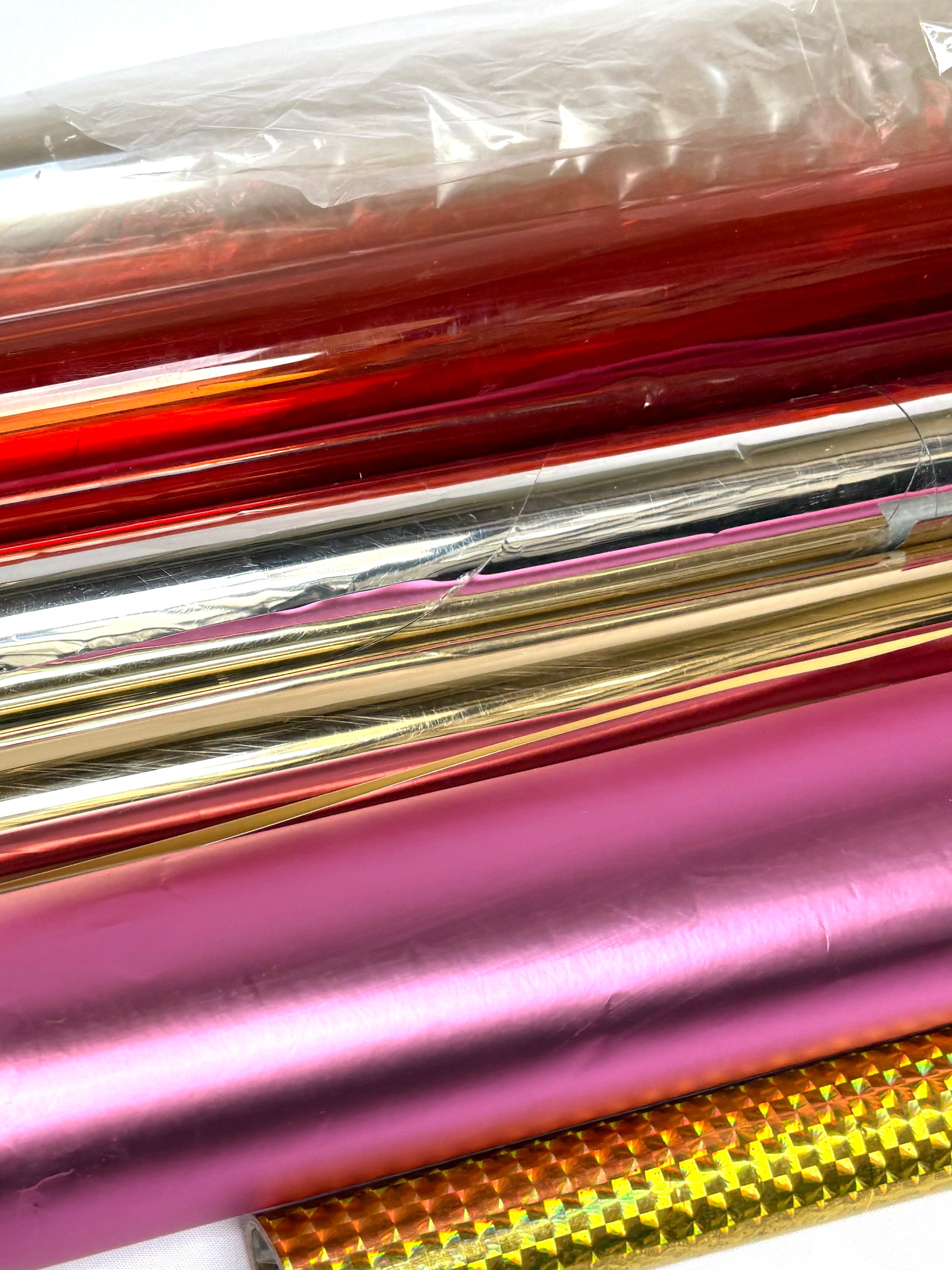 Close-up of collection of colourful glossy paper plastic rolls 