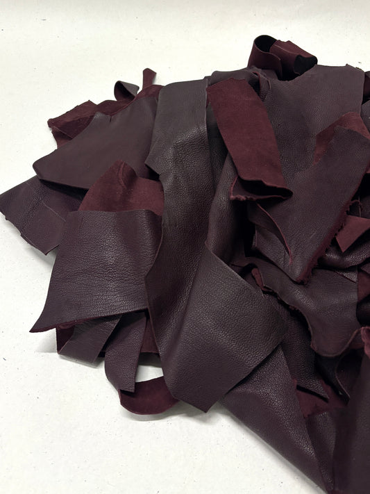 Close-up of a pile of burgundy red leather offcuts with various sizes 