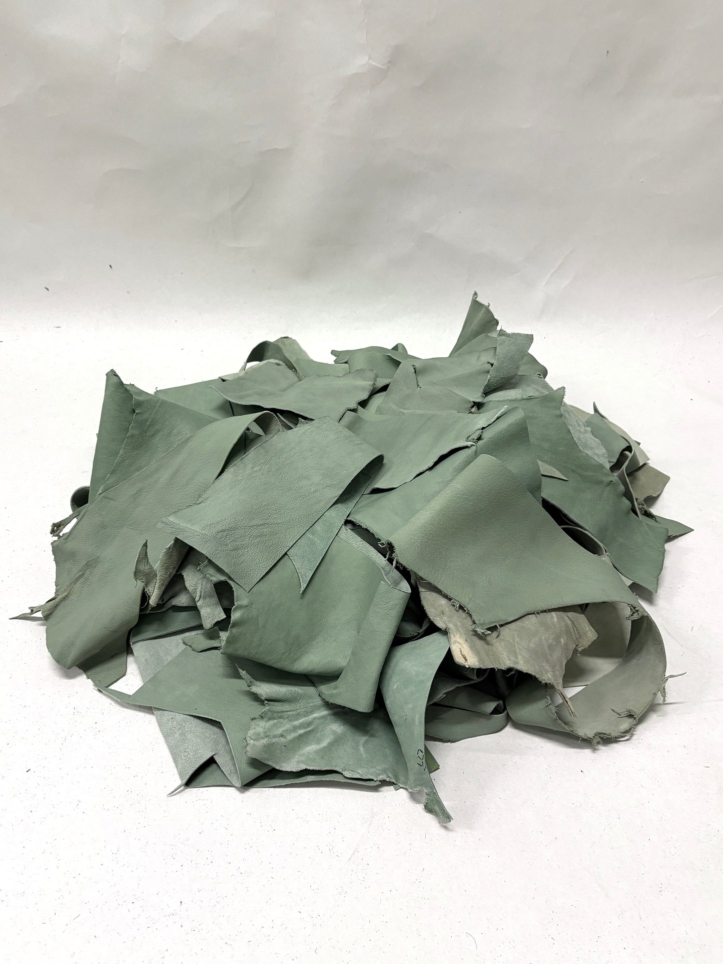 Pile of mint green leather offcuts with various sizes 