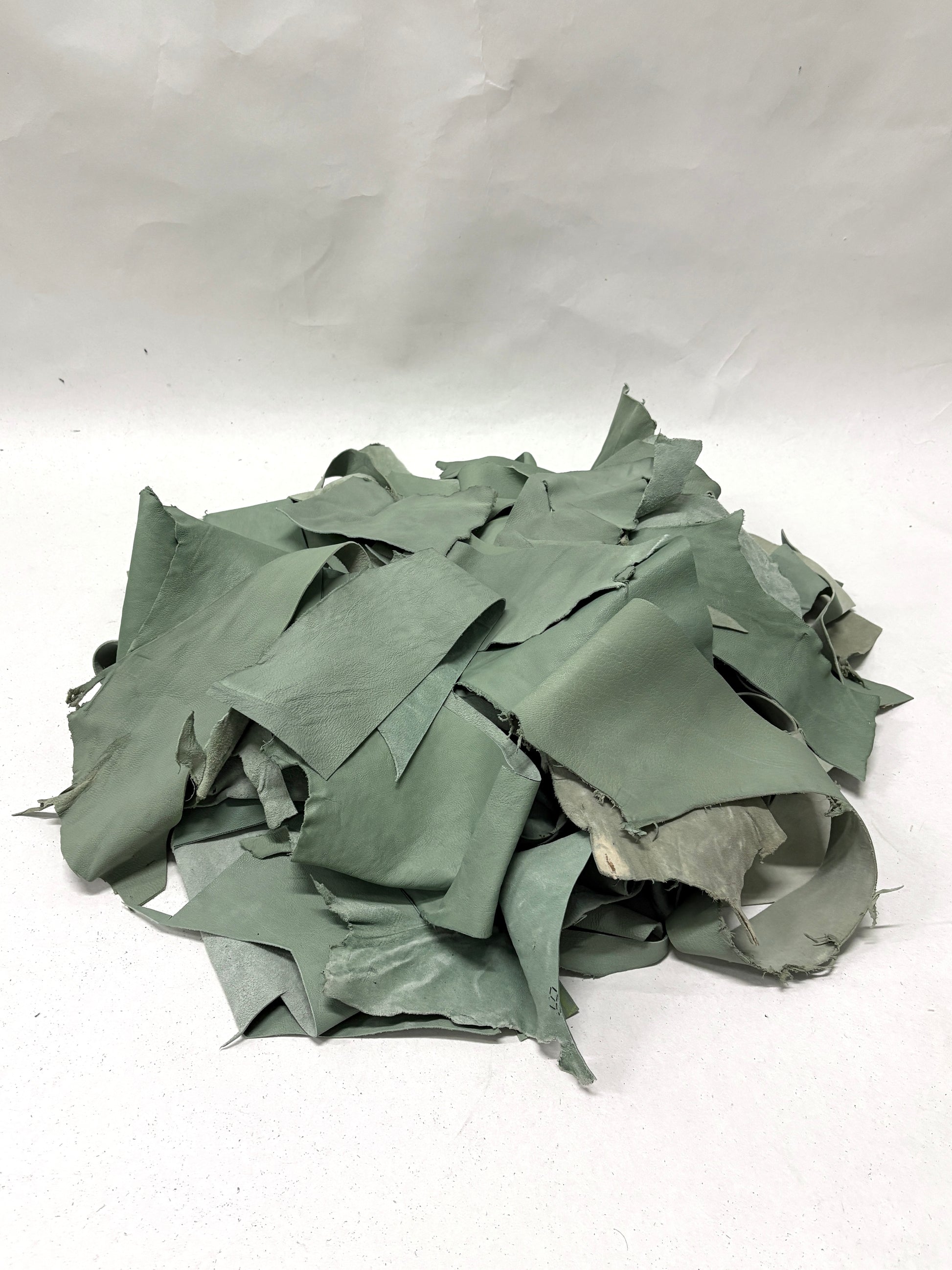 Pile of mint green leather offcuts with various sizes 