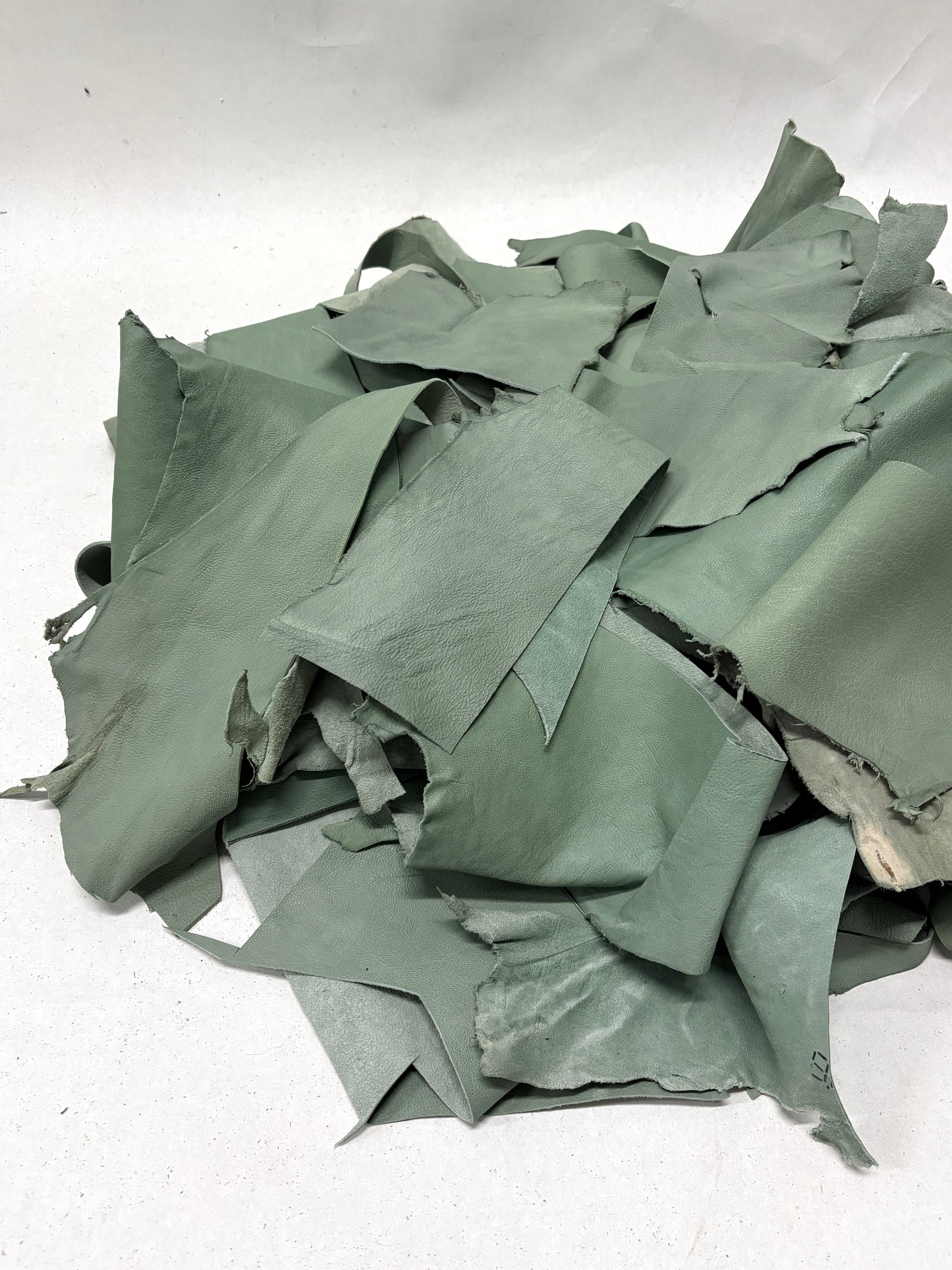 Pile of mint green leather offcuts with various sizes 