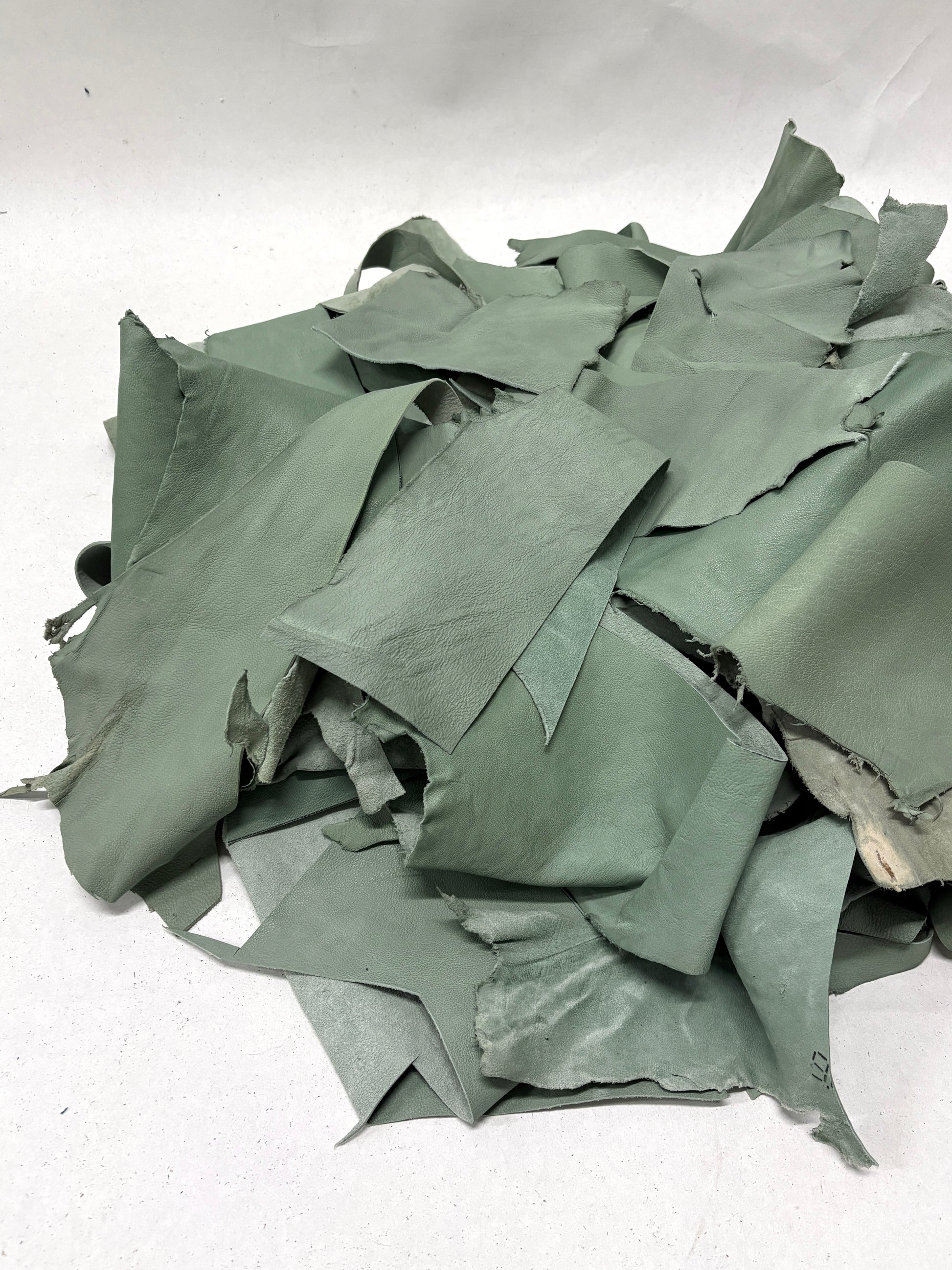 Pile of mint green leather offcuts with various sizes 