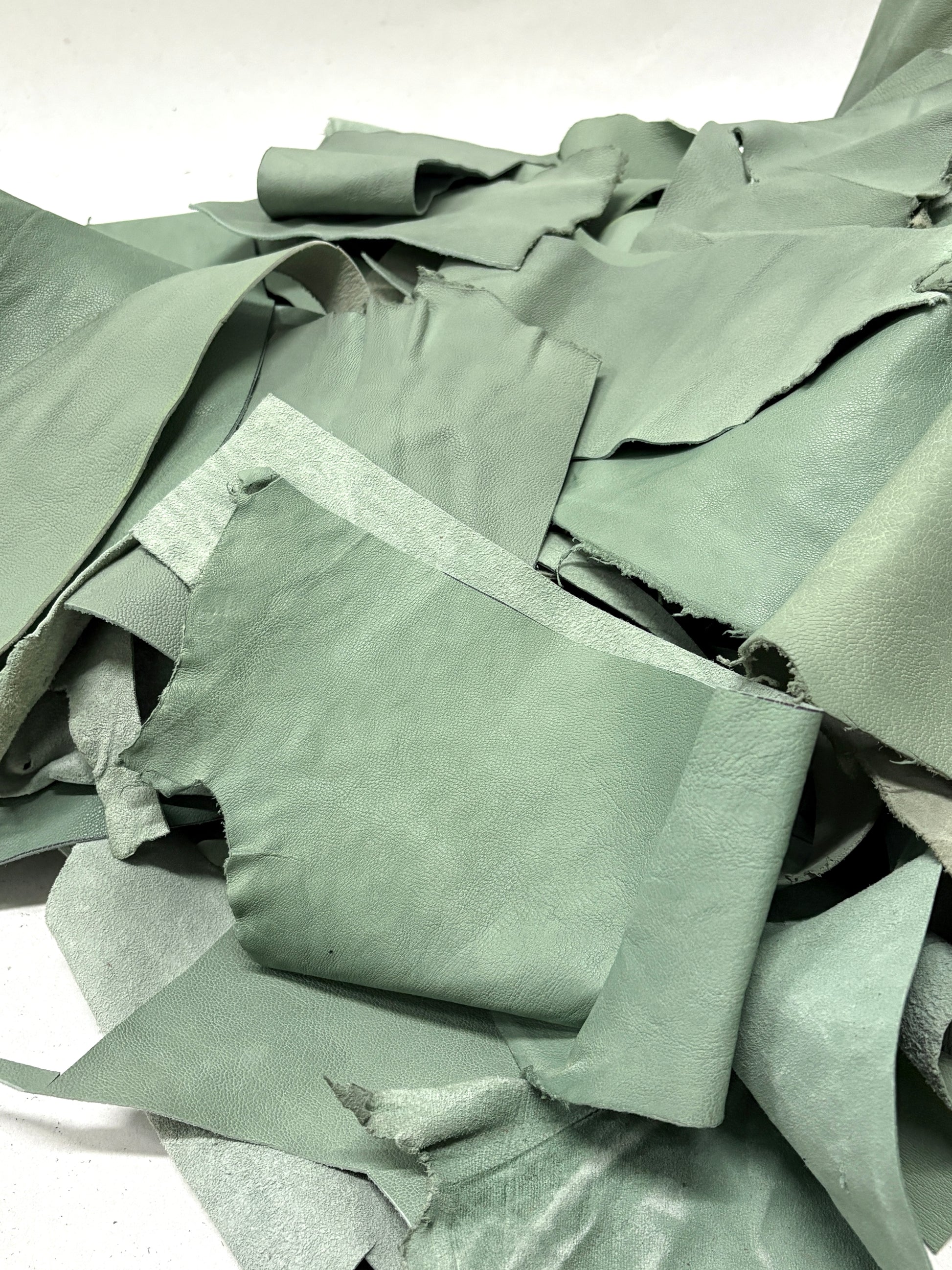 Close-up of pile of mint green leather offcuts with various sizes 