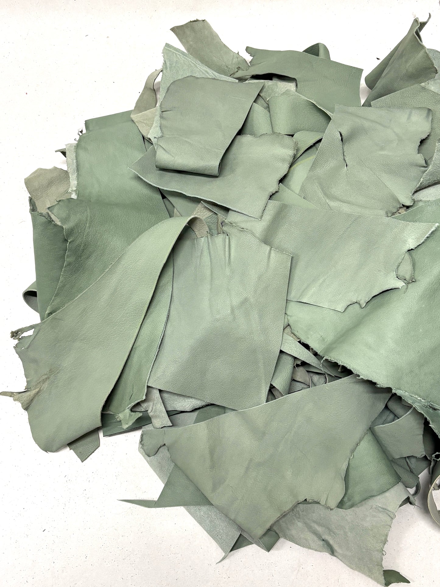Pile of mint green leather offcuts with various sizes 