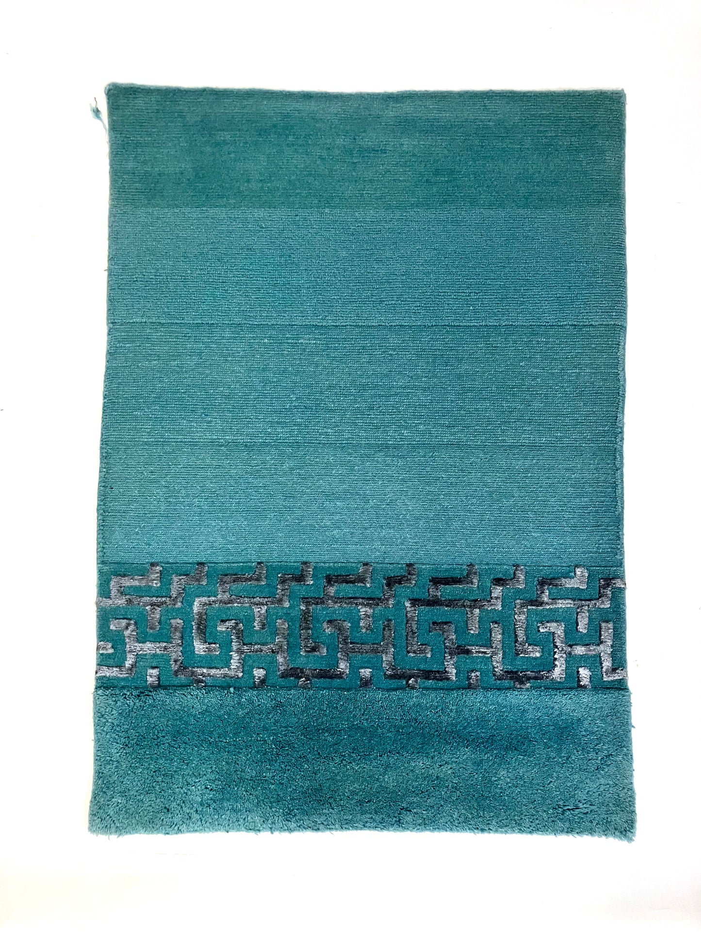 A hand knotted rug with green and silver geometric patterns 