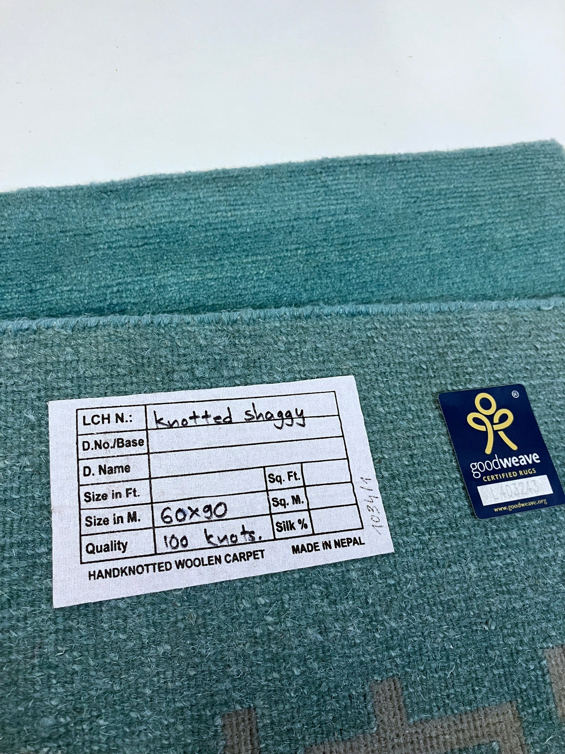 Close-up of hand knotted rug with a tag containing its details