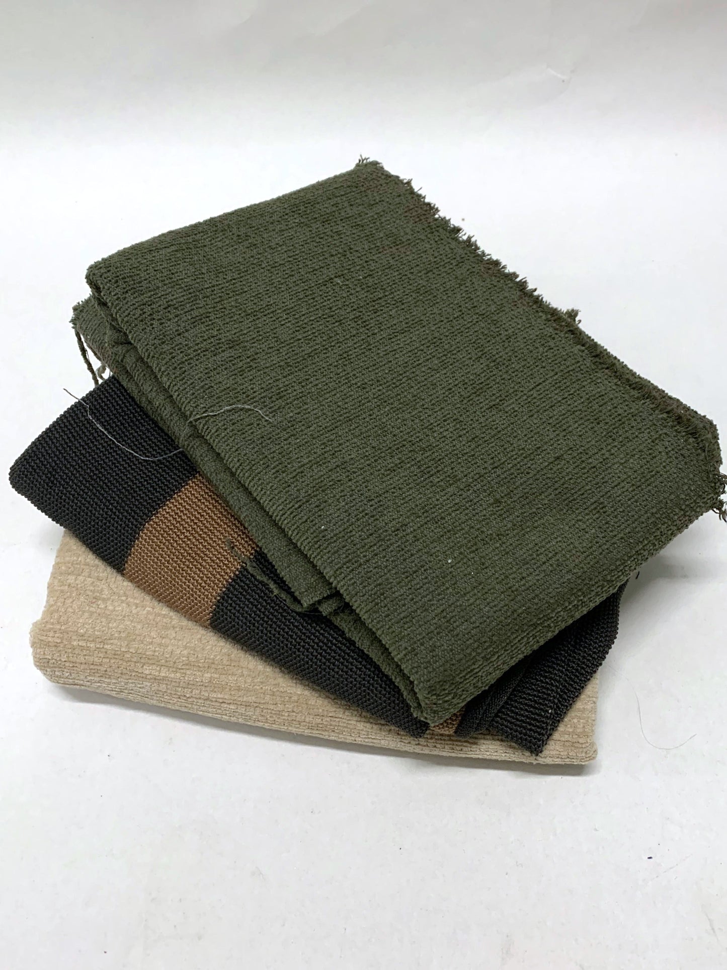 Pile of heavy weight fabric with green, brown, cream white