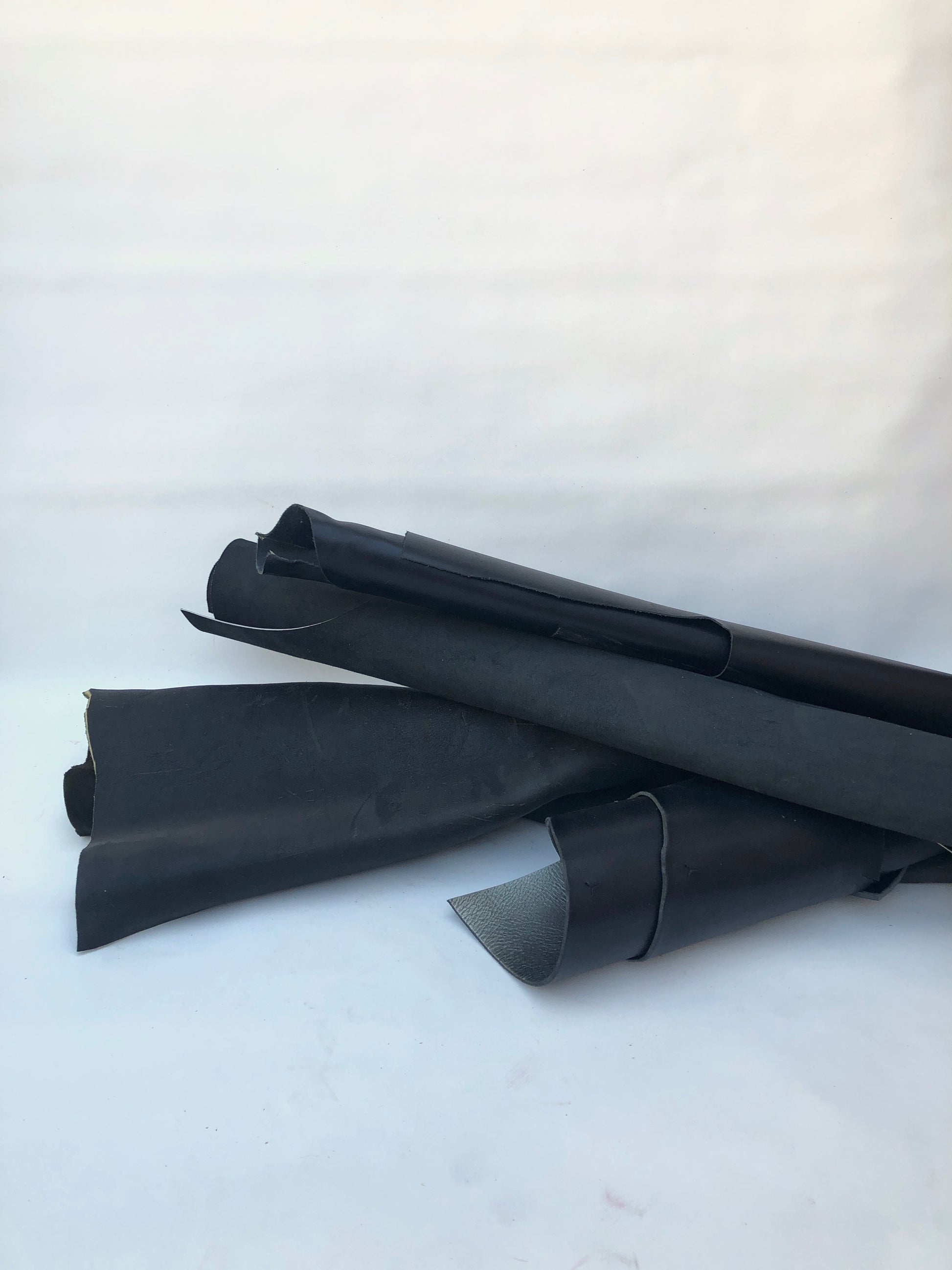 Three black rolled leather 