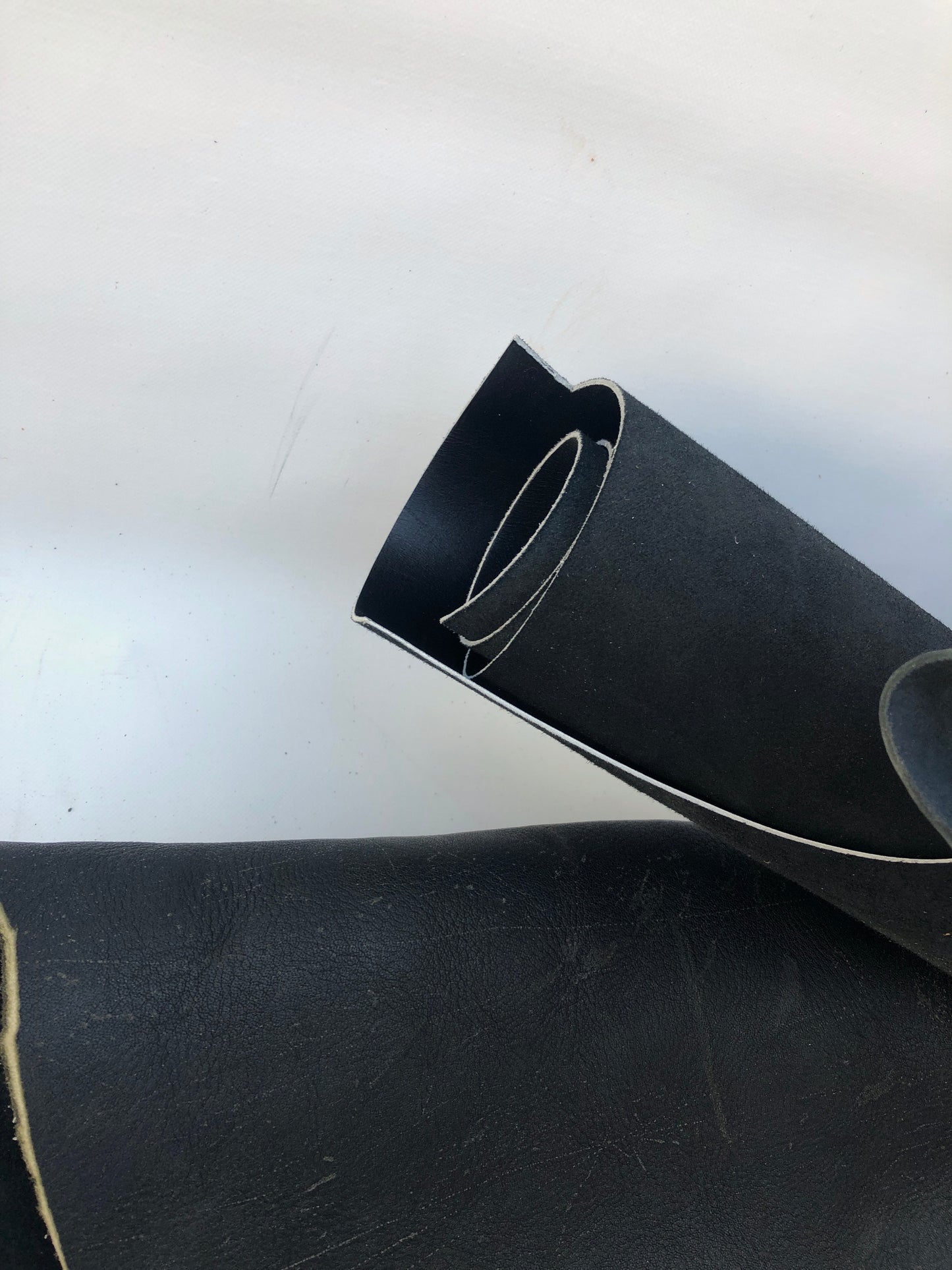Close-up of black rolled leather with some scars 