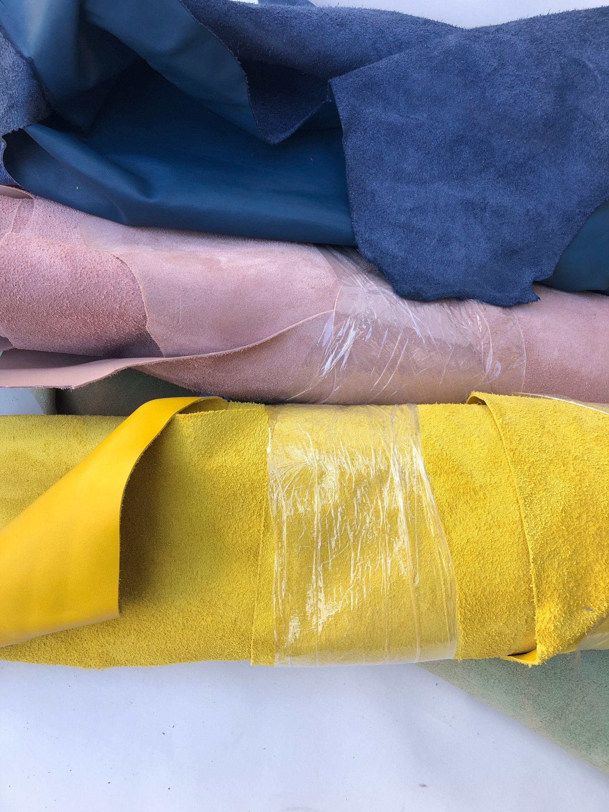 Close-up of blue, pink and yellow rolled leather with visible texture 