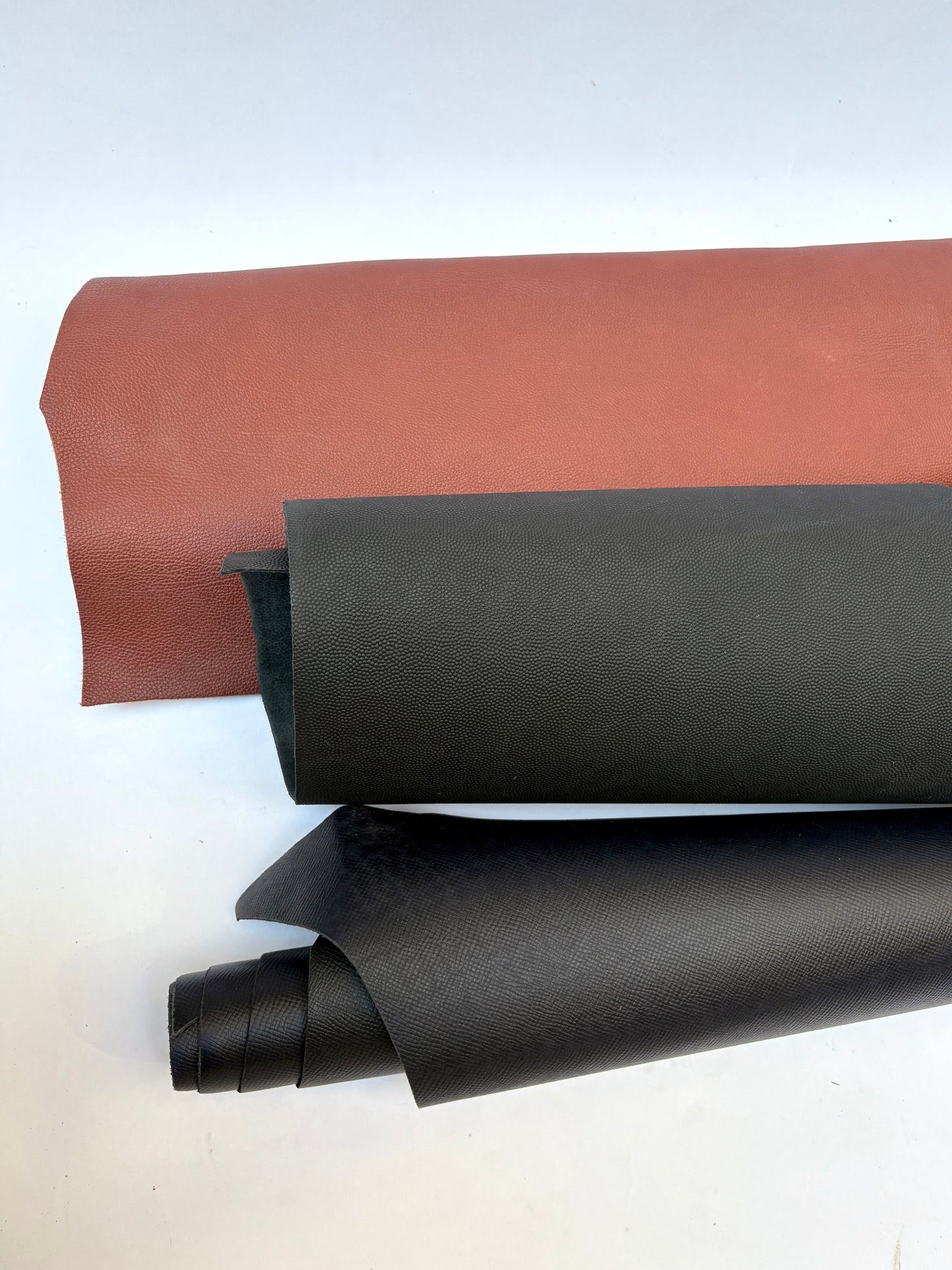 Two rolls of leather, one brown and one black