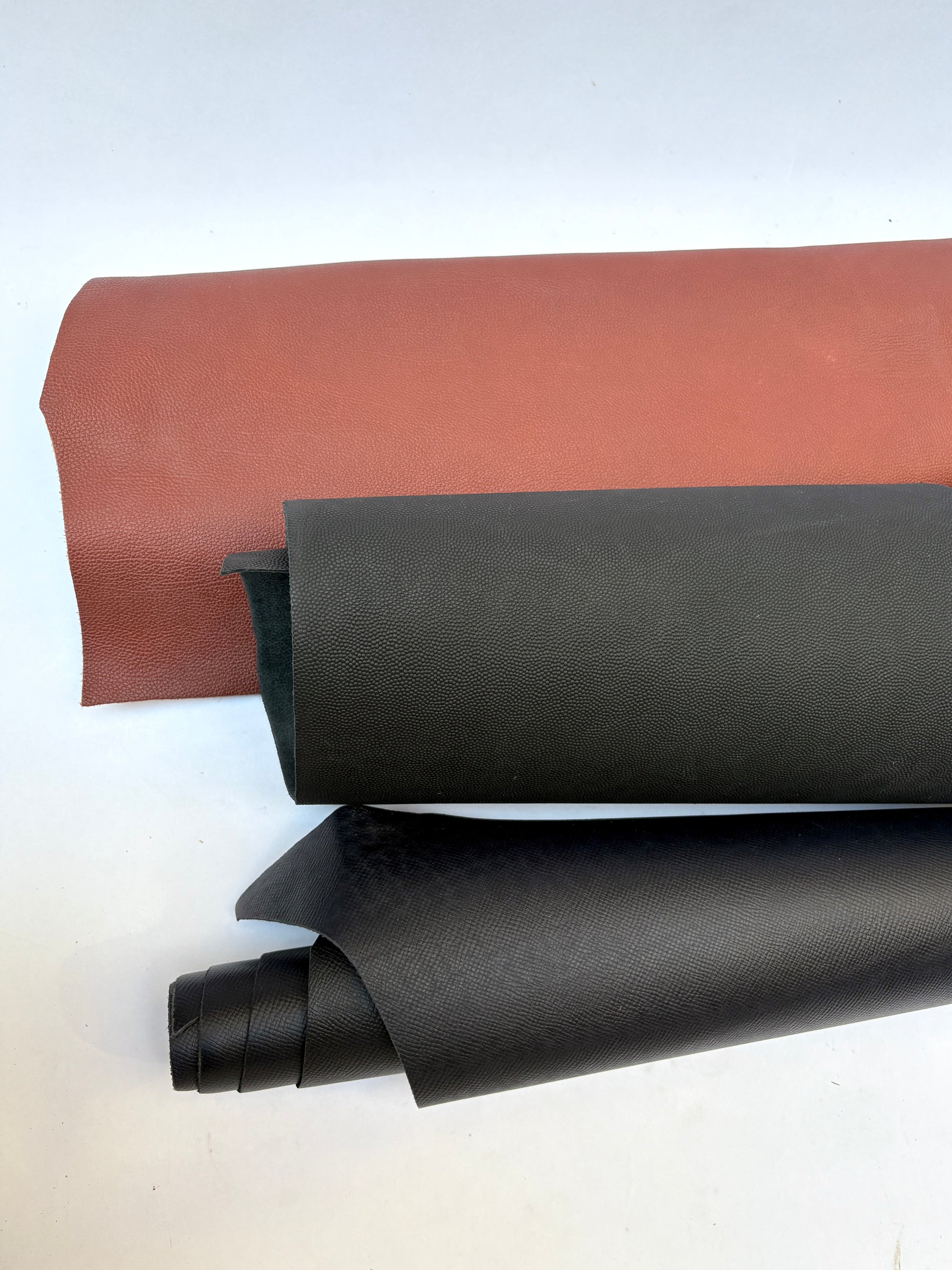 Two rolls of leather, one brown and one black