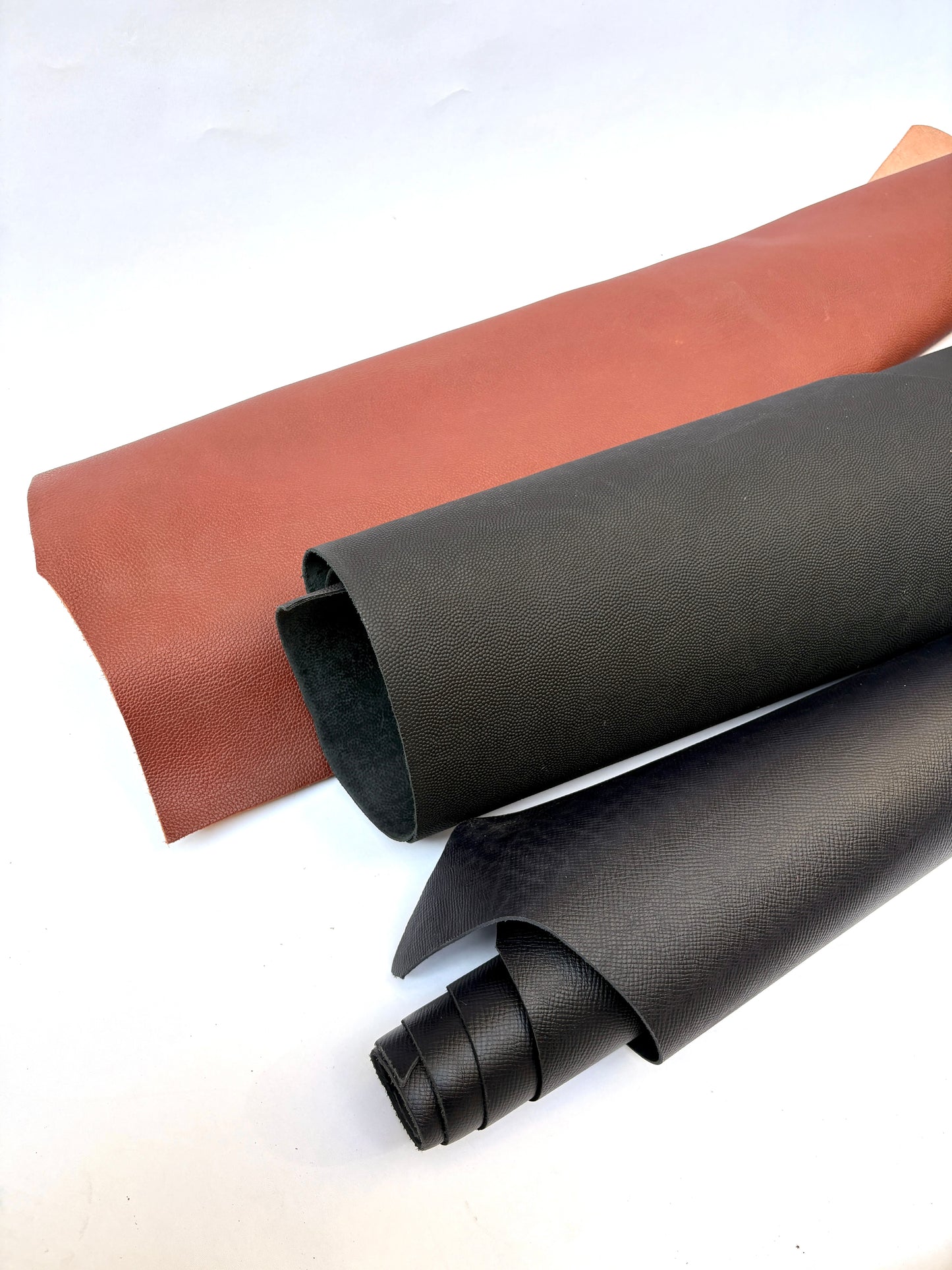 Two rolls of brown and black leather 