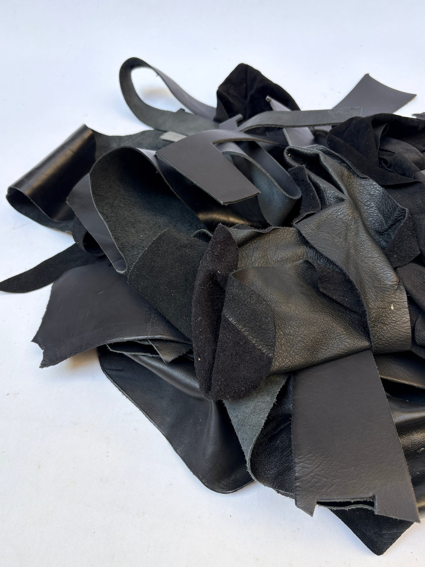 Close-up of a pile of black leather offcuts with various textures 