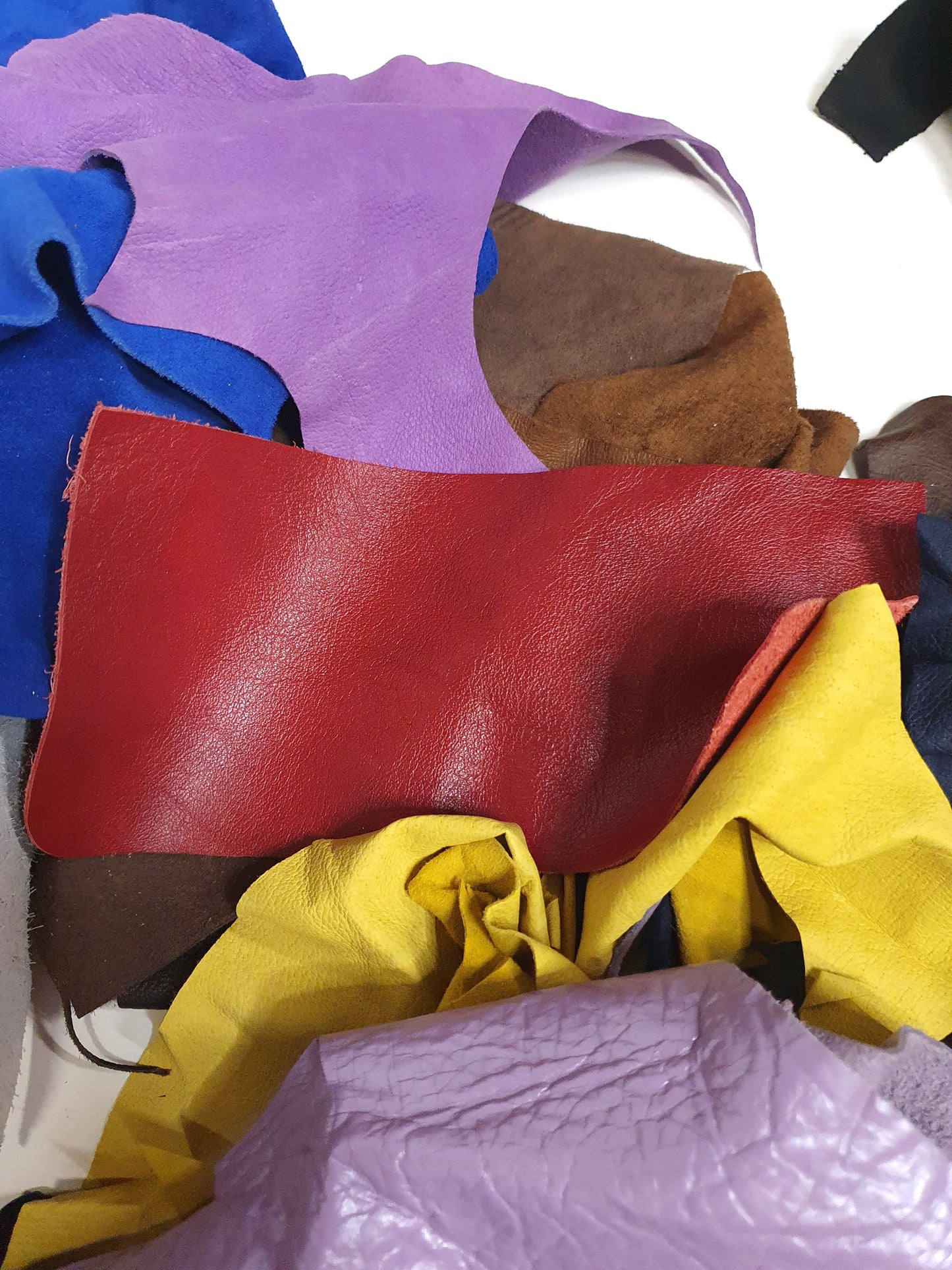 Pile of colourful leather offcuts with various textures and sizes 