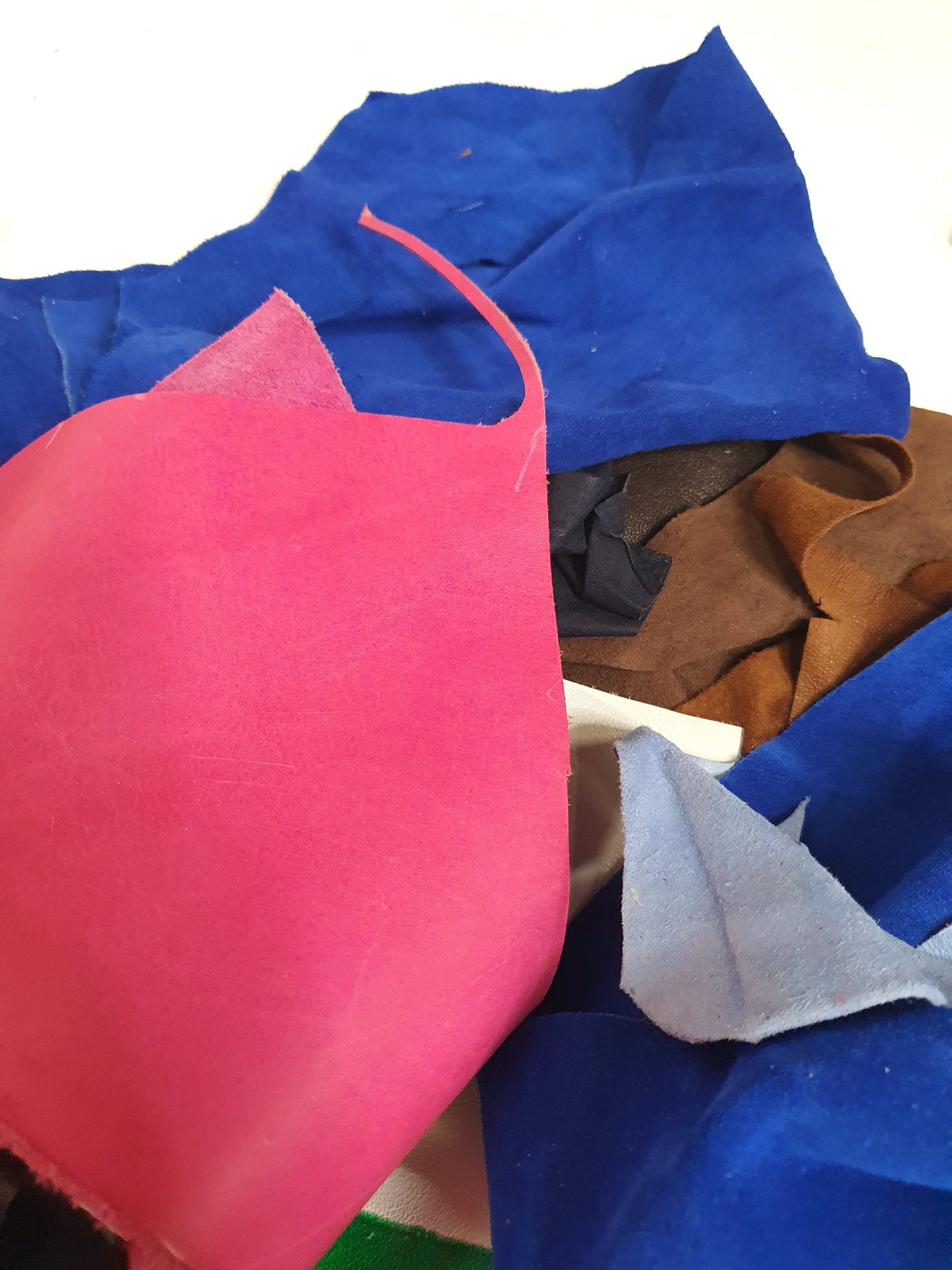 Close-up of leather offcuts with pink, blue and brown 