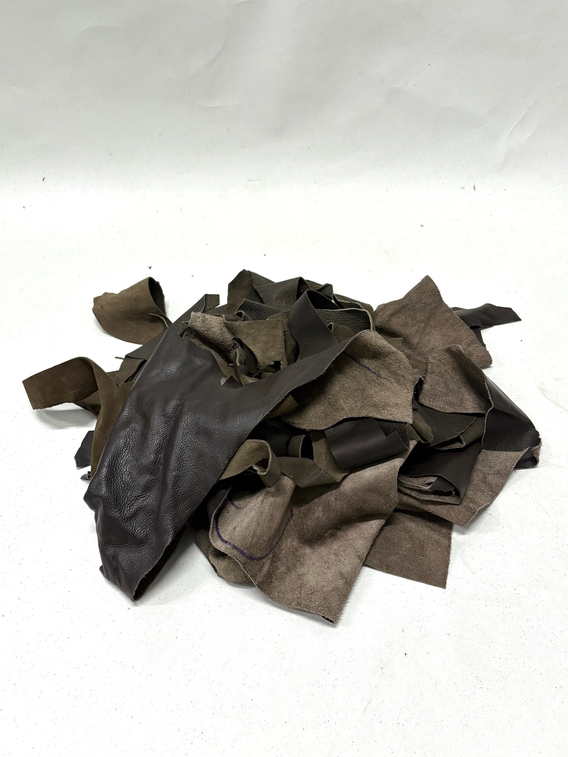 Pile of dark brown leather offcuts with various types of textures