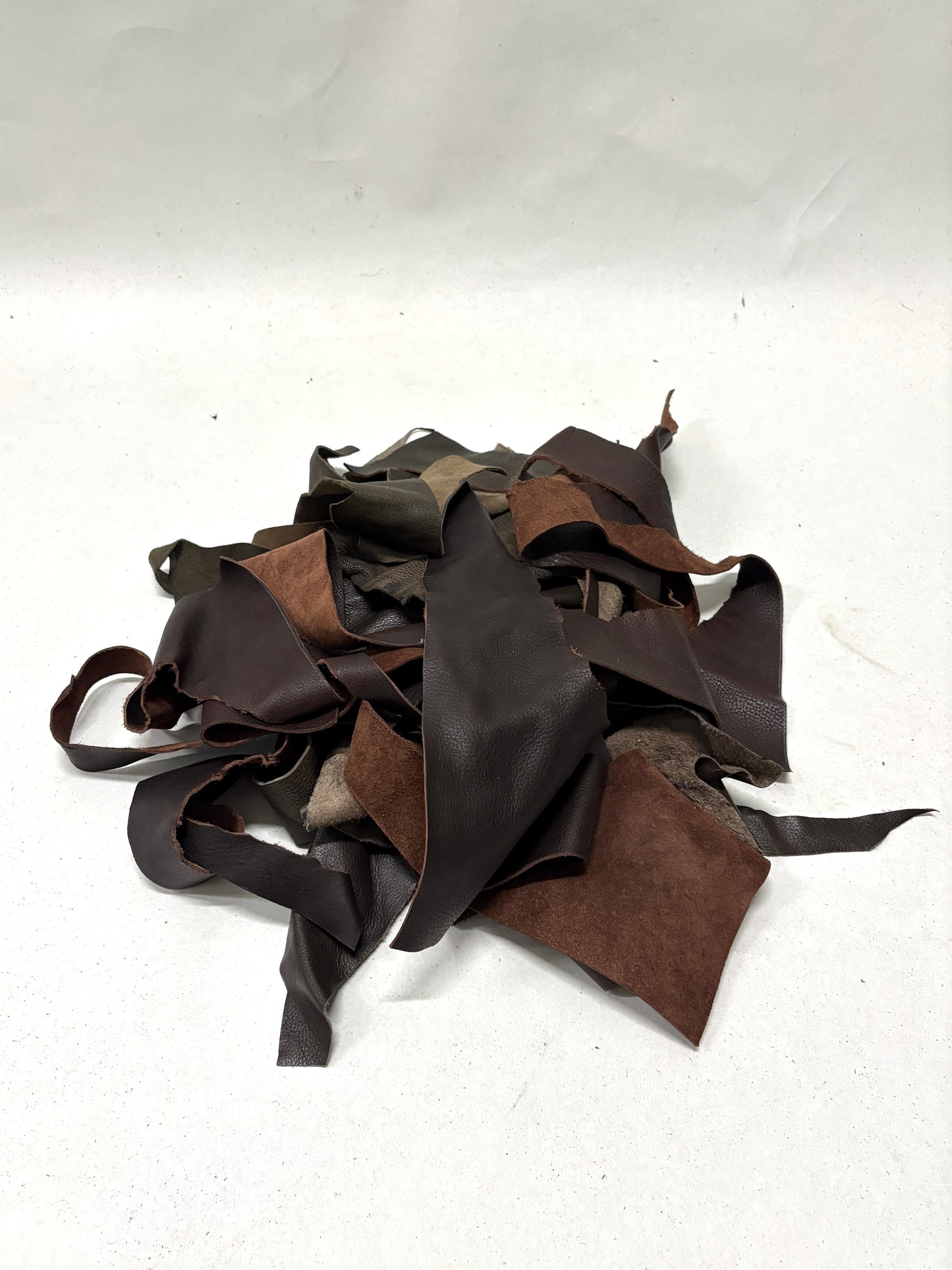 Pile of dark brown leather offcuts with various types of textures