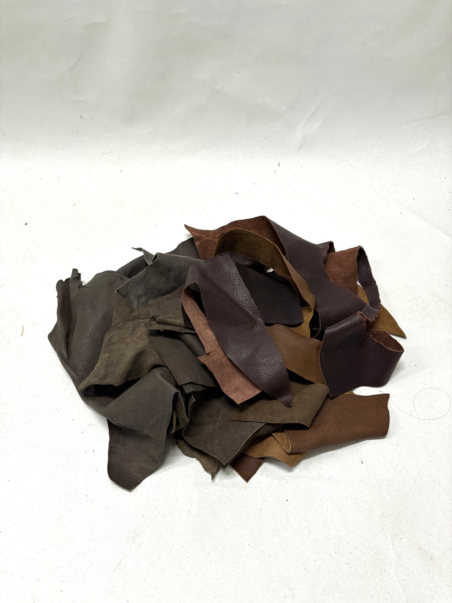 Pile of dark brown leather offcuts with various textures 