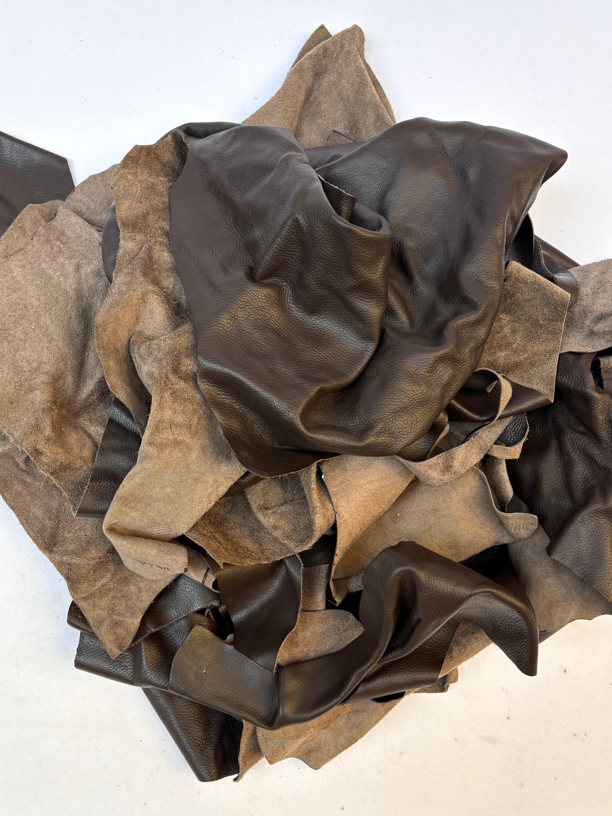 Pile of dark brown leather offcuts with various sizes