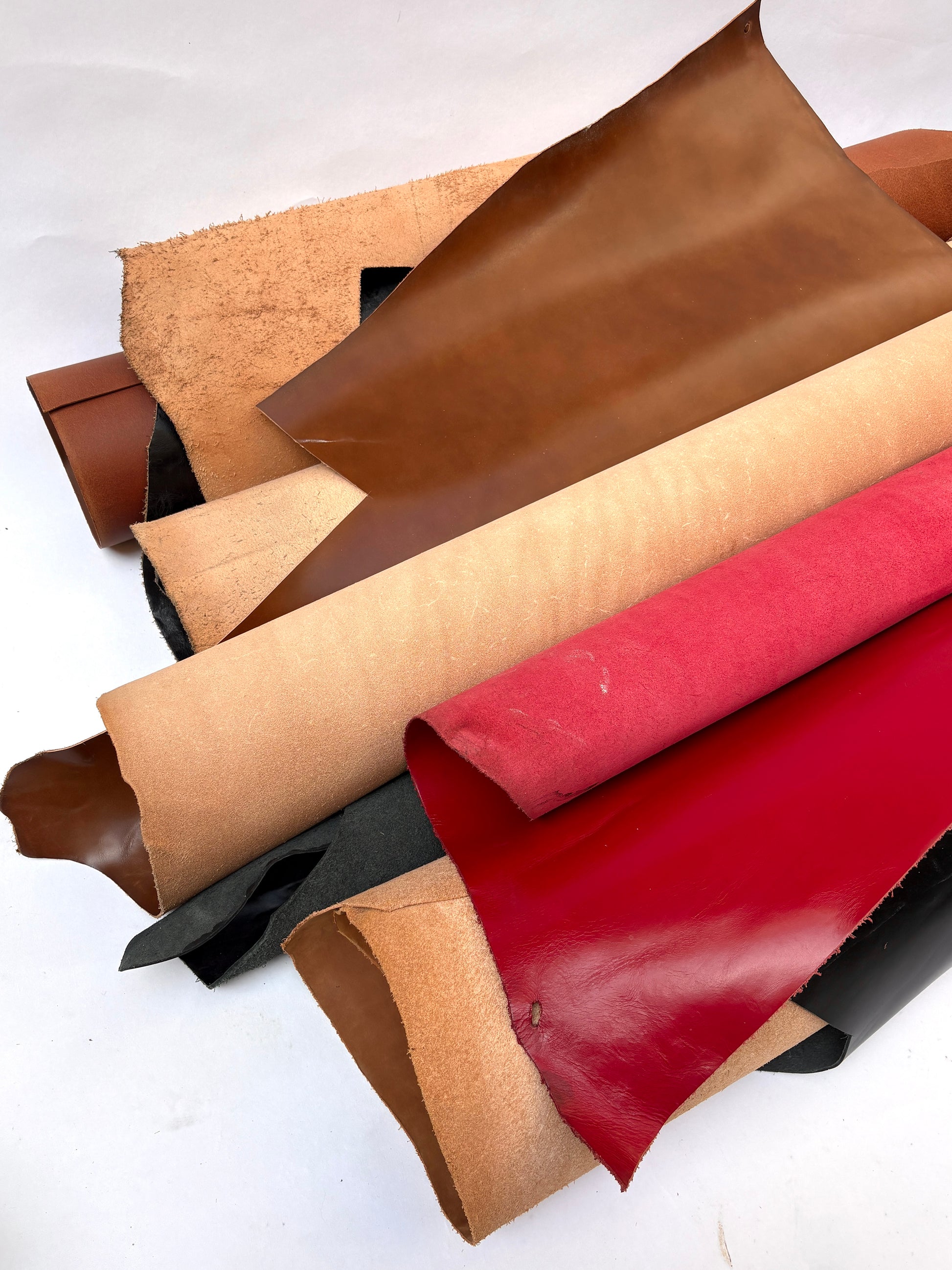 Collection of leather in brown, beige, and red with visible marking lines