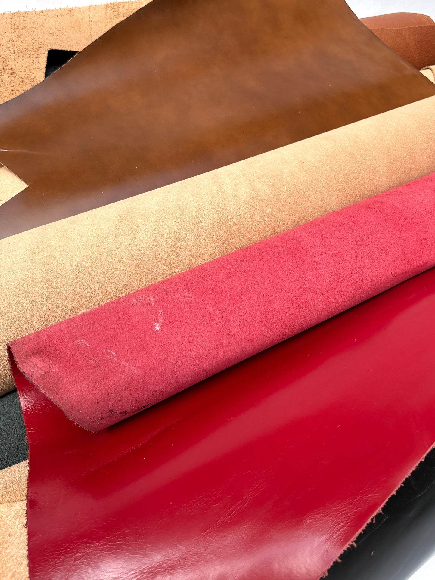 Collection of leather in brown, beige, and red with visible marking lines