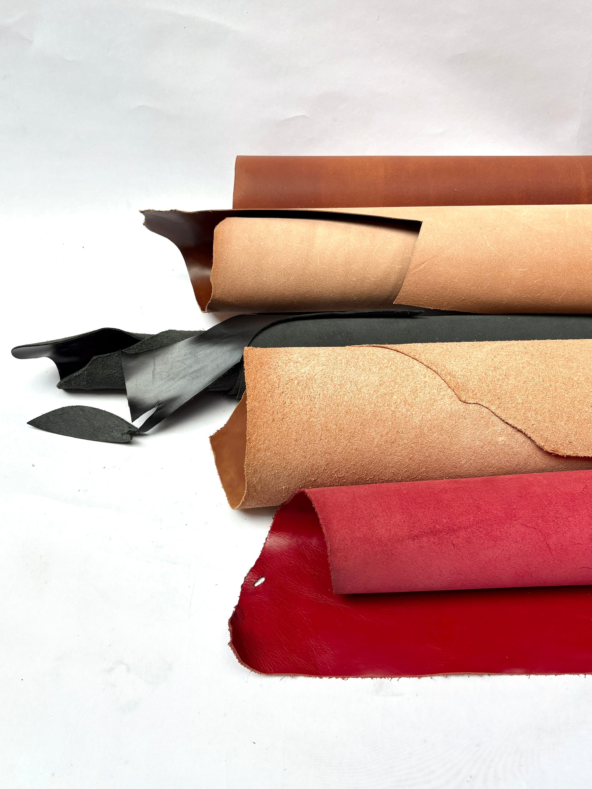 Collection of rolled leather in brown, black, and red, with some holes