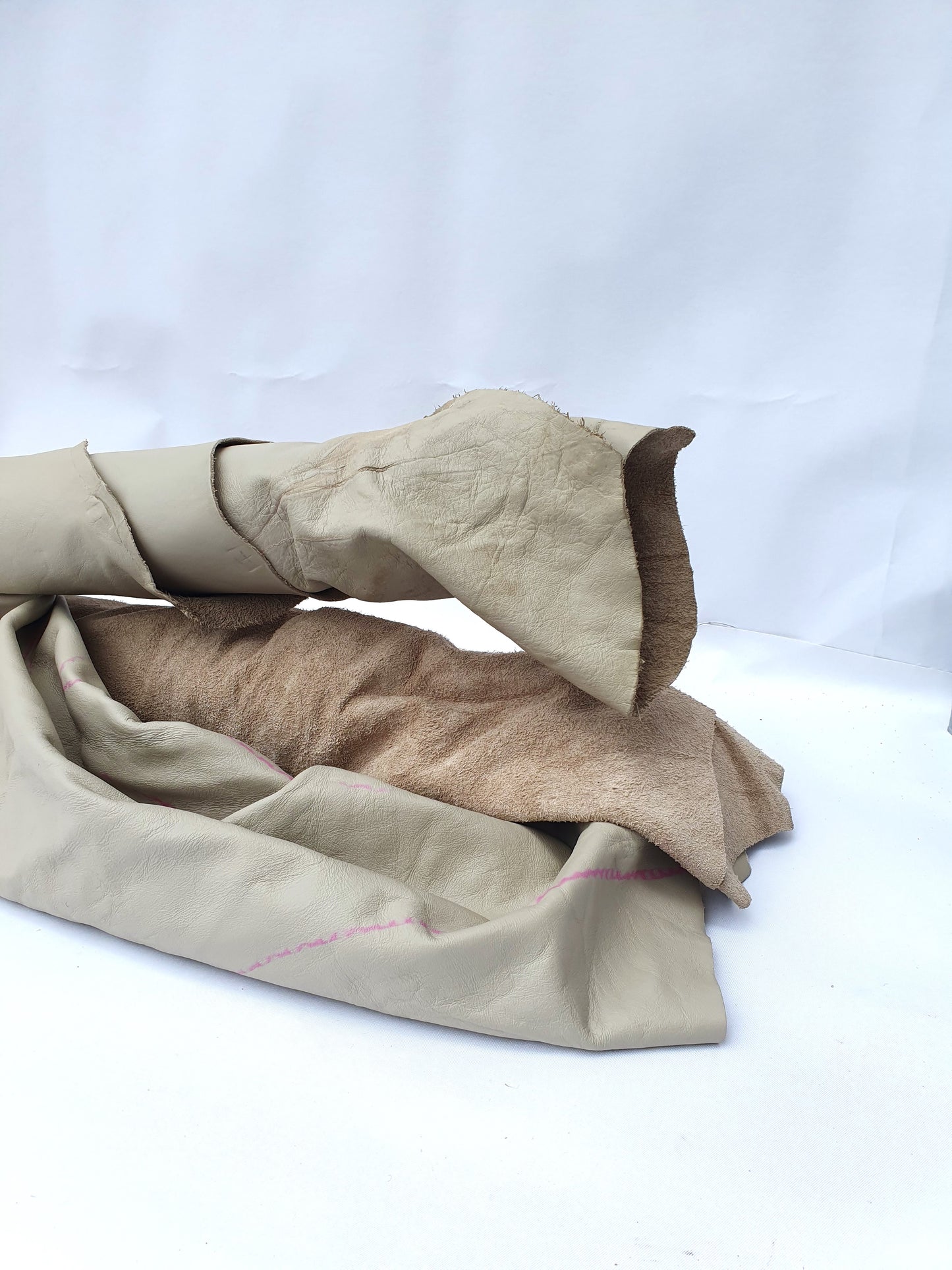 Two beige coloured rolled leather with visible marking lines 