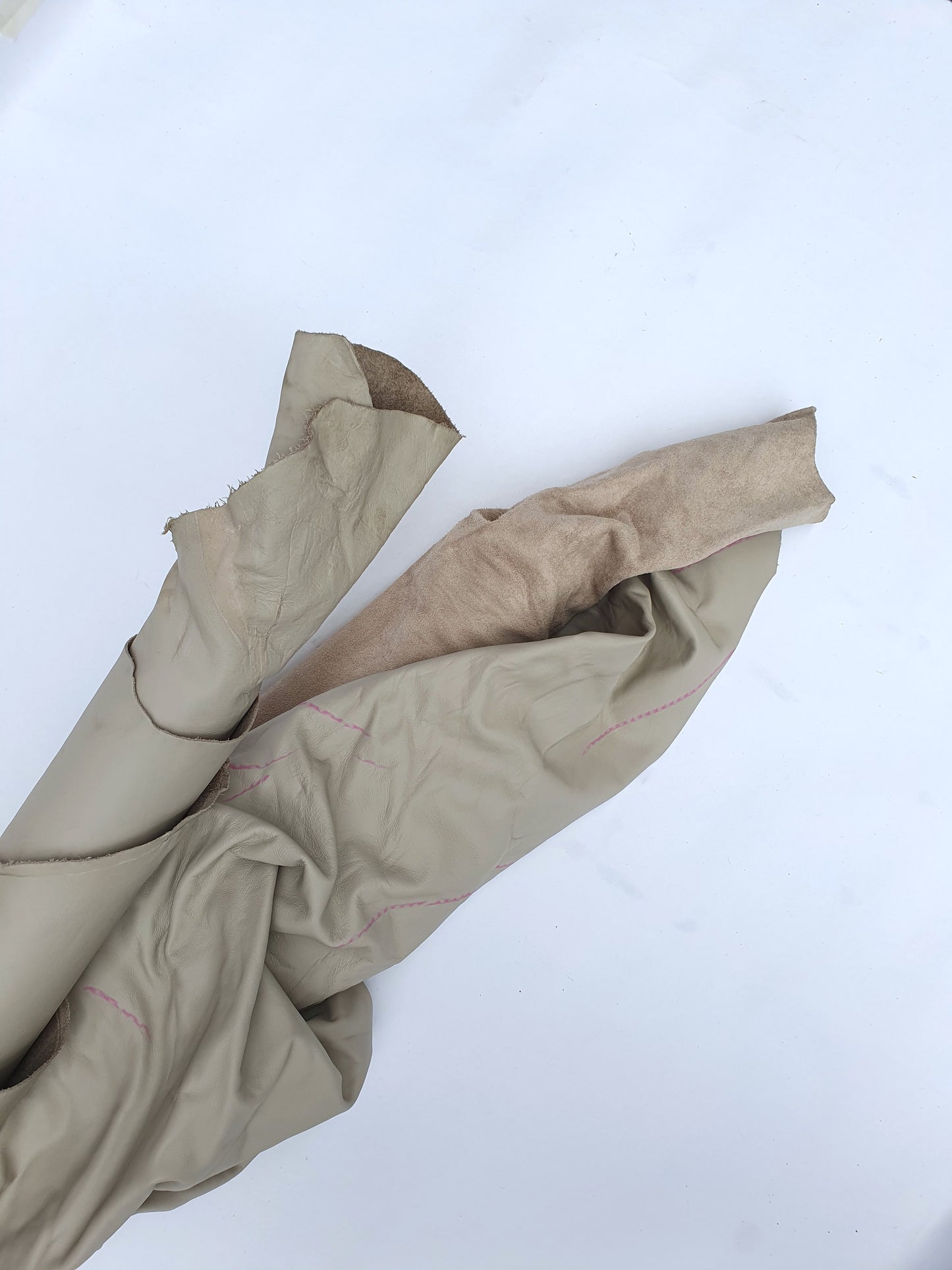 Two beige coloured rolled leather with visible marking lines 