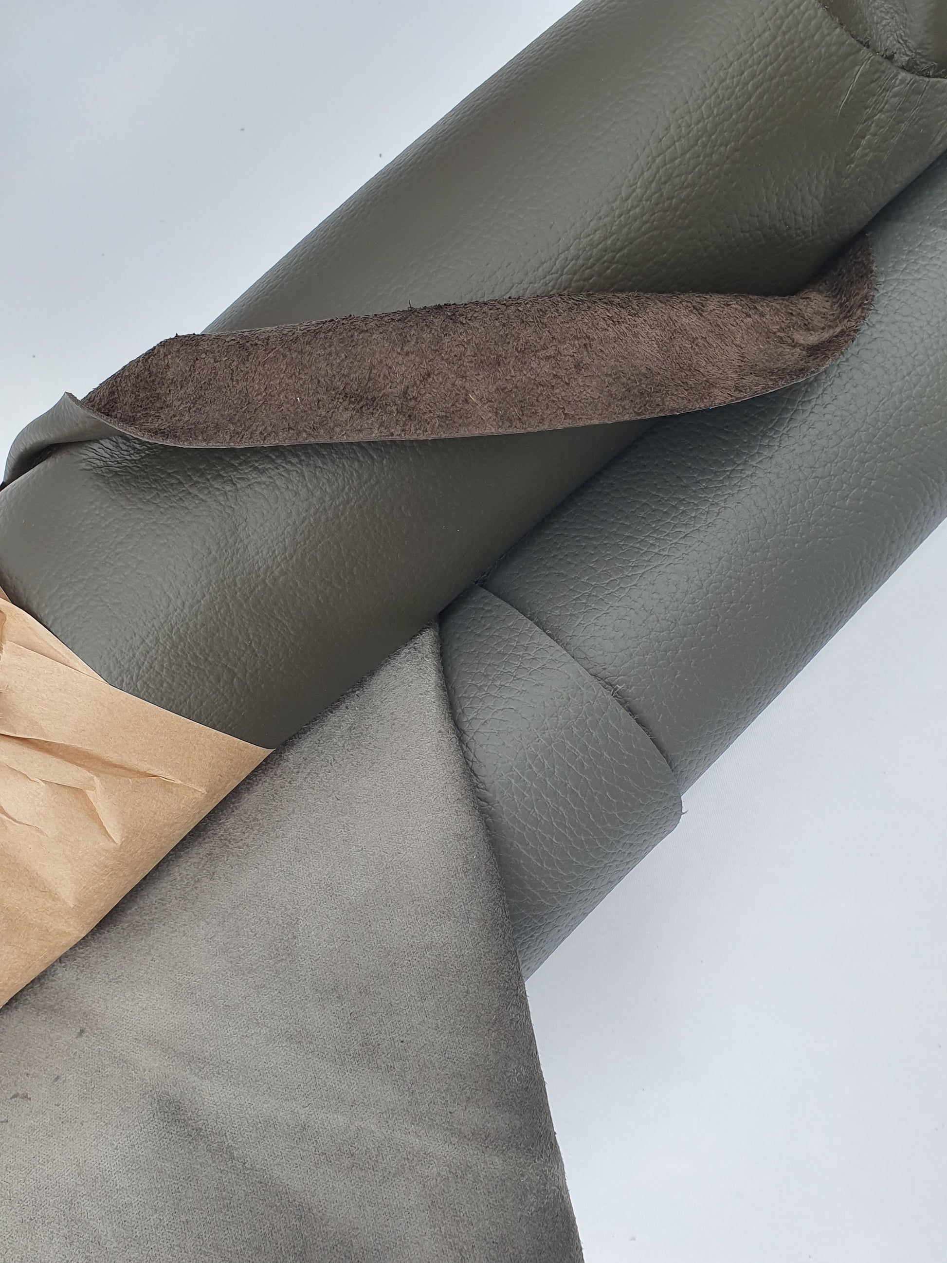 Close-up of rolled dark grey to brown leather showing a soft texture and folded edge