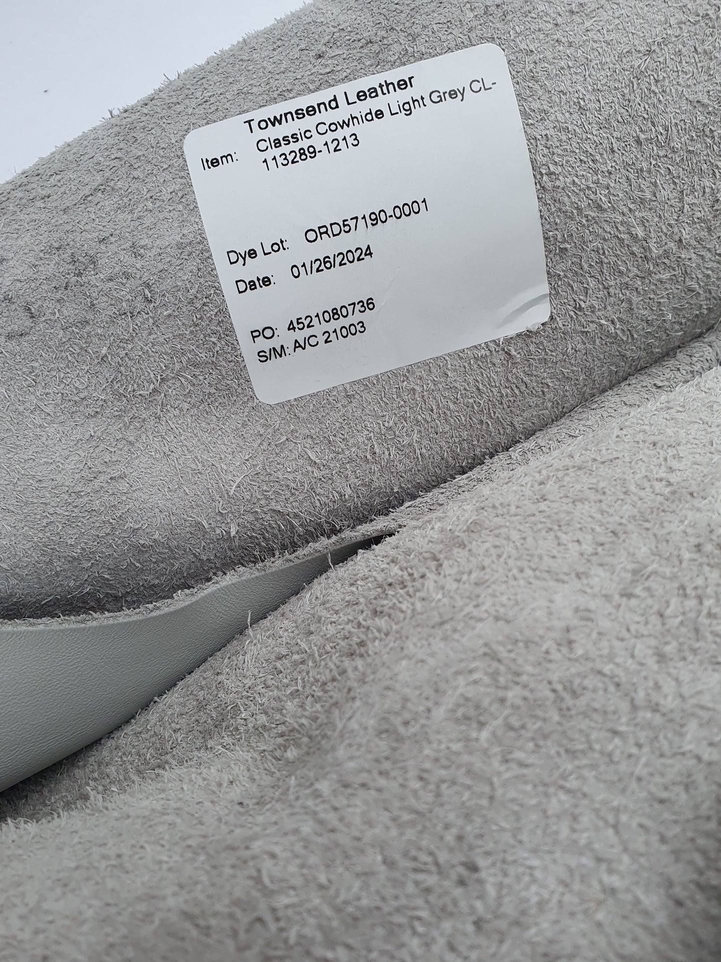 Unfolded leather in grey and light grey with a label containing its details