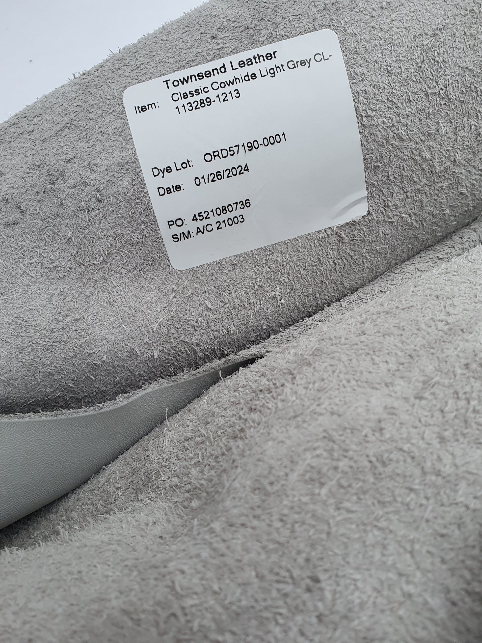 Unfolded leather in grey and light grey with a label containing its details