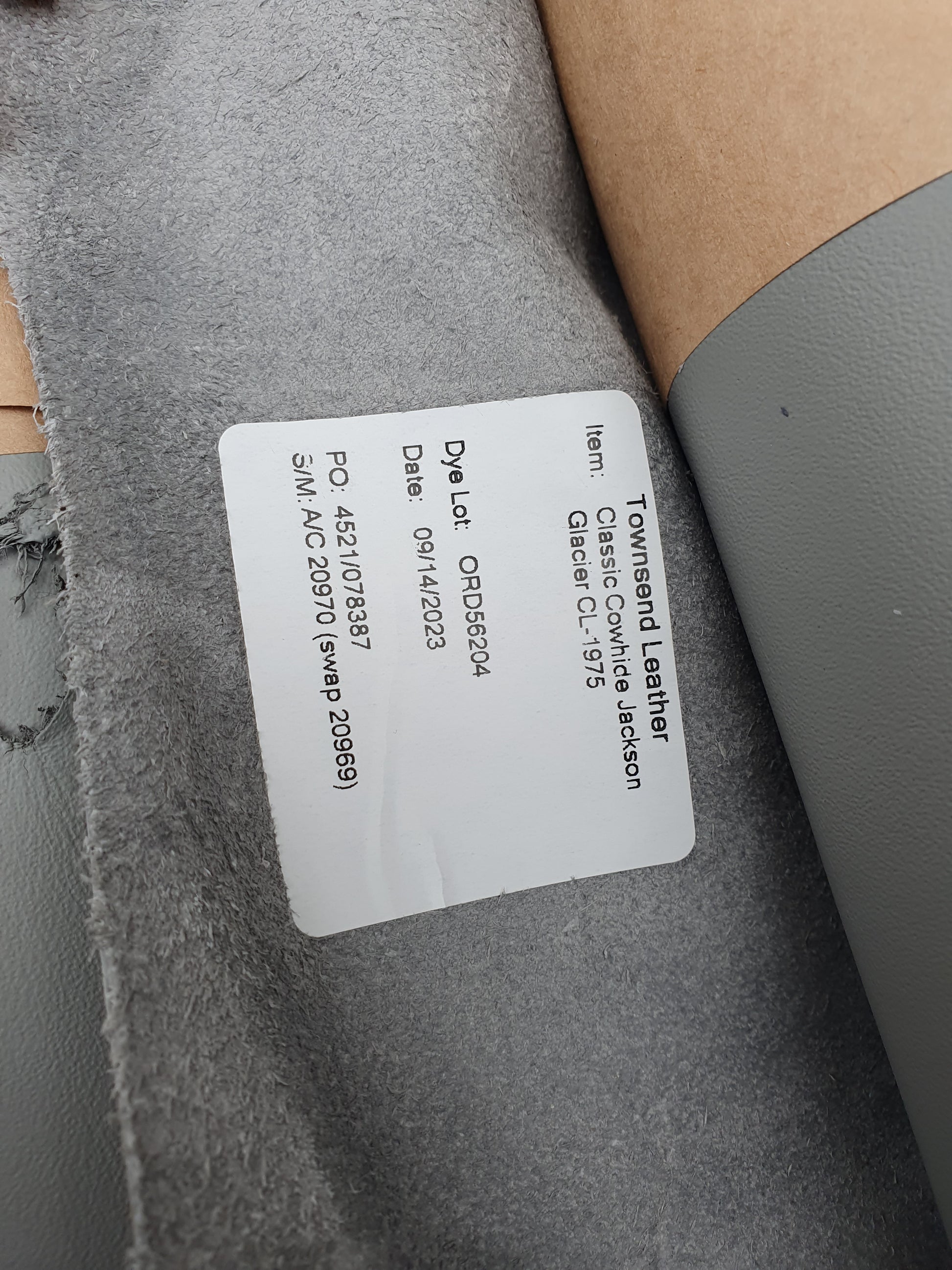 Two rolled leather in grey and light grey with a label containing its details