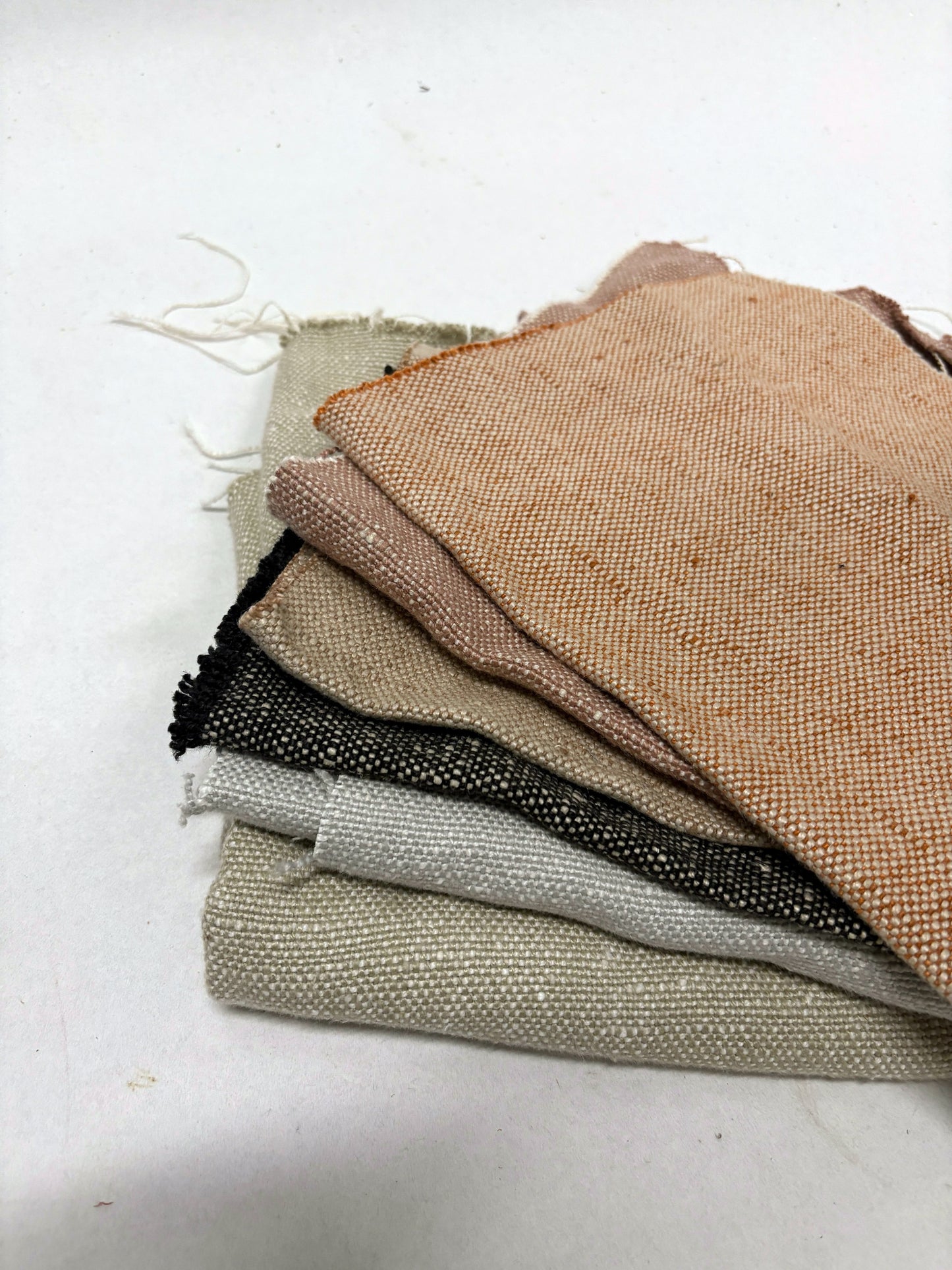 Stack of linen fabric swatches in various colours, texture visible