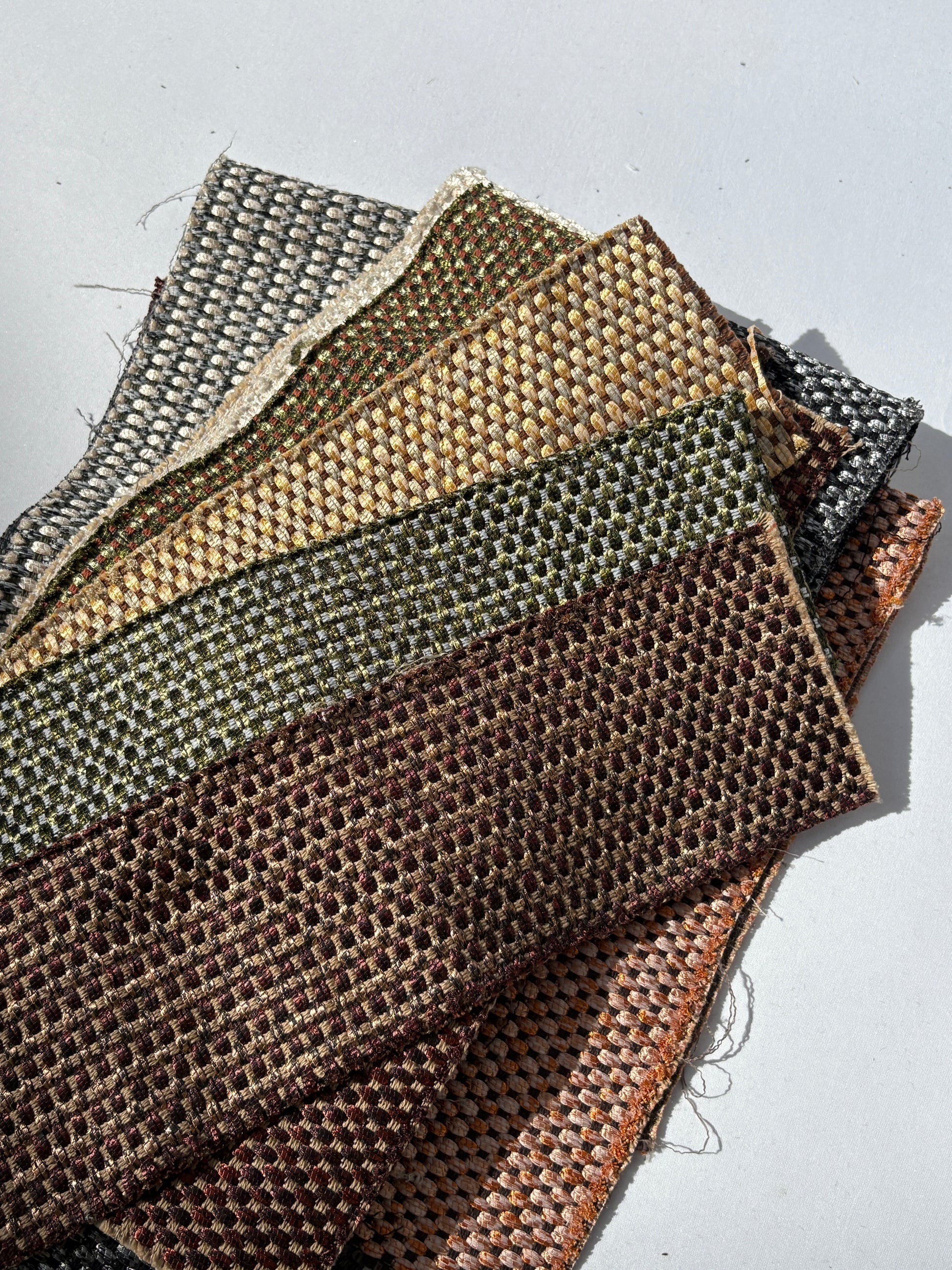 Mixed bundle of long fabric offcuts with shimmer woven patterns on white.
