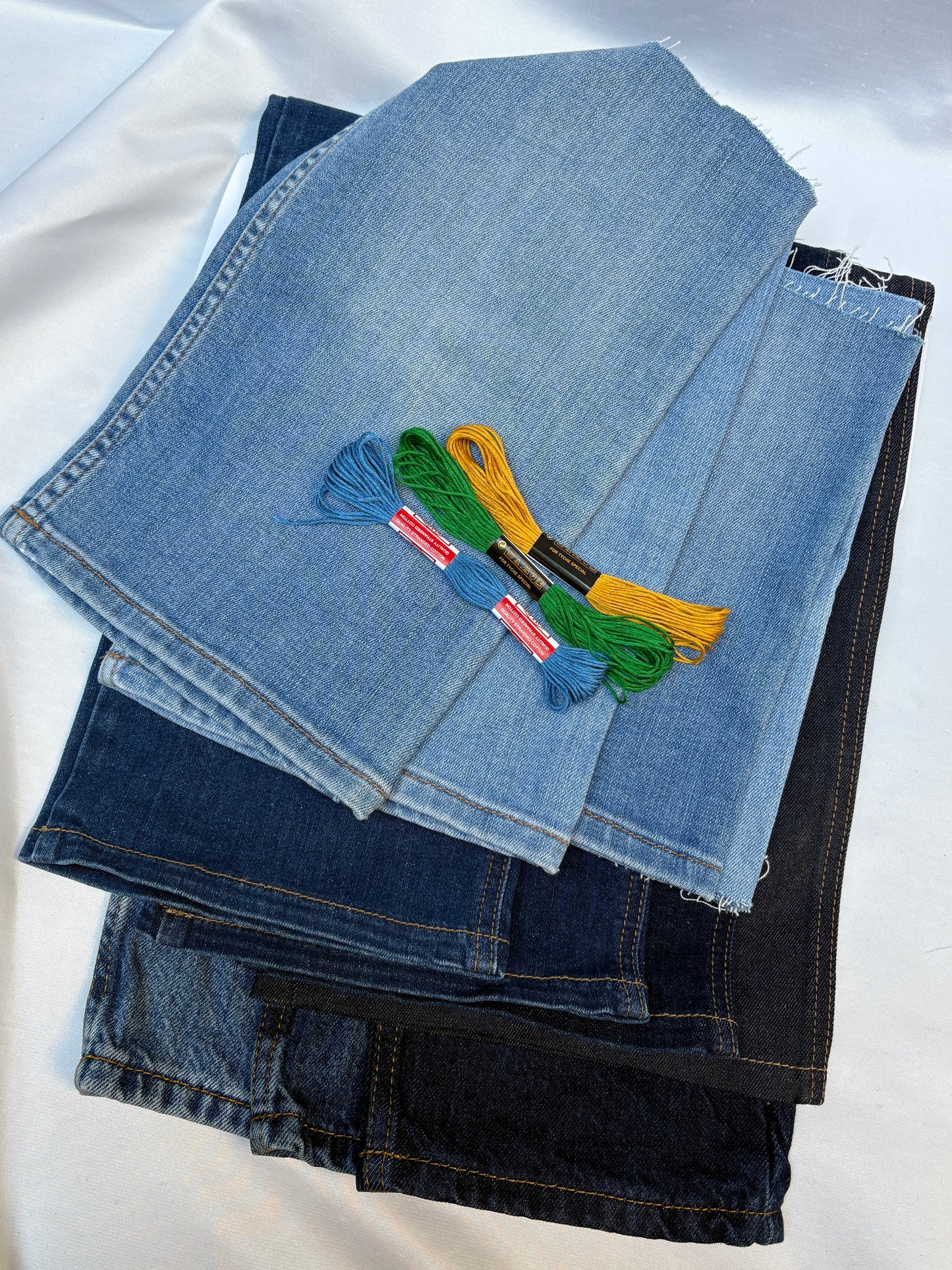 Layered denim fabric pieces in mixed washes with contrasting embroidery threads.