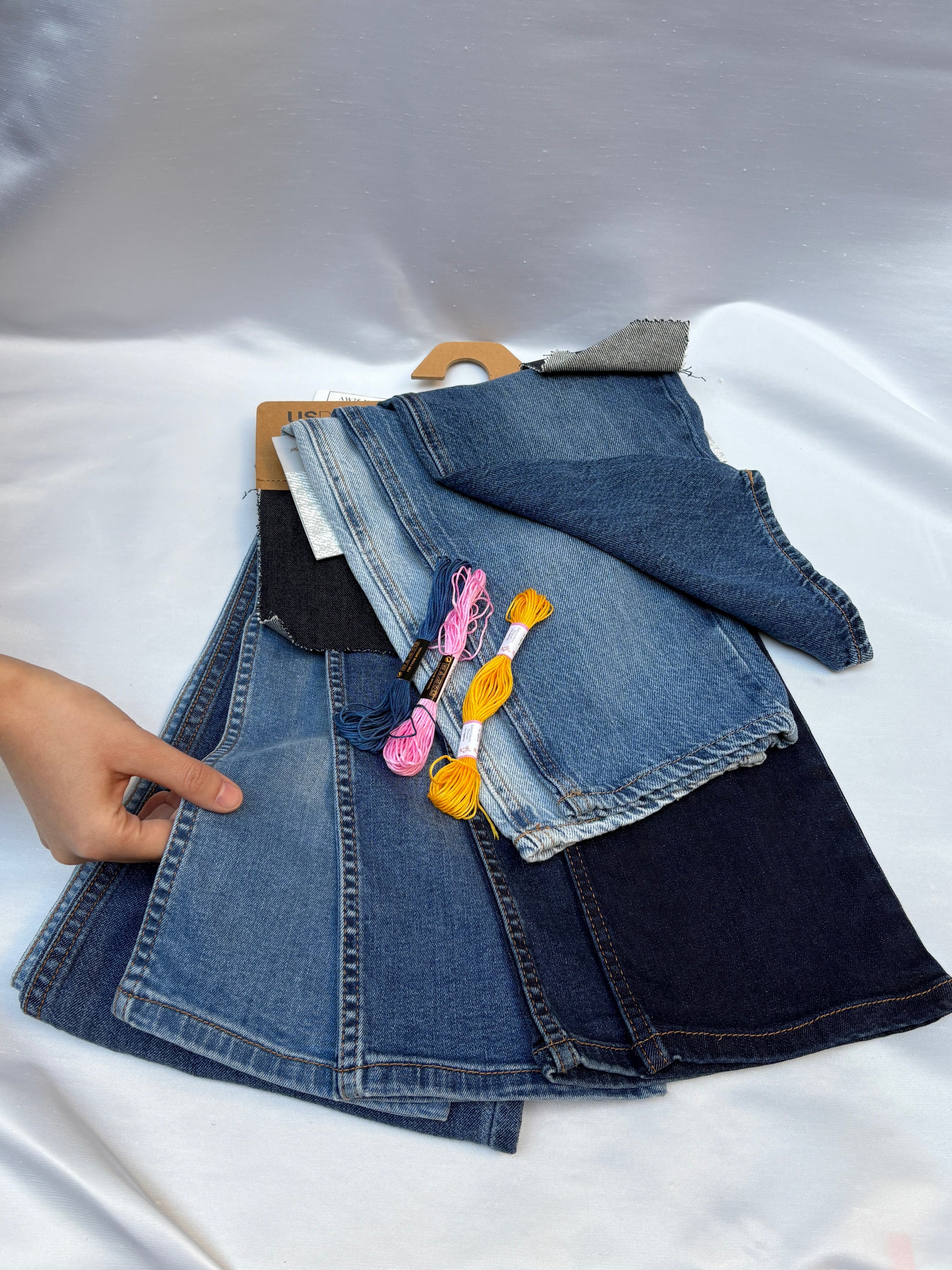 Assorted denim fabric pieces in mixed washes with colourful embroidery threads.