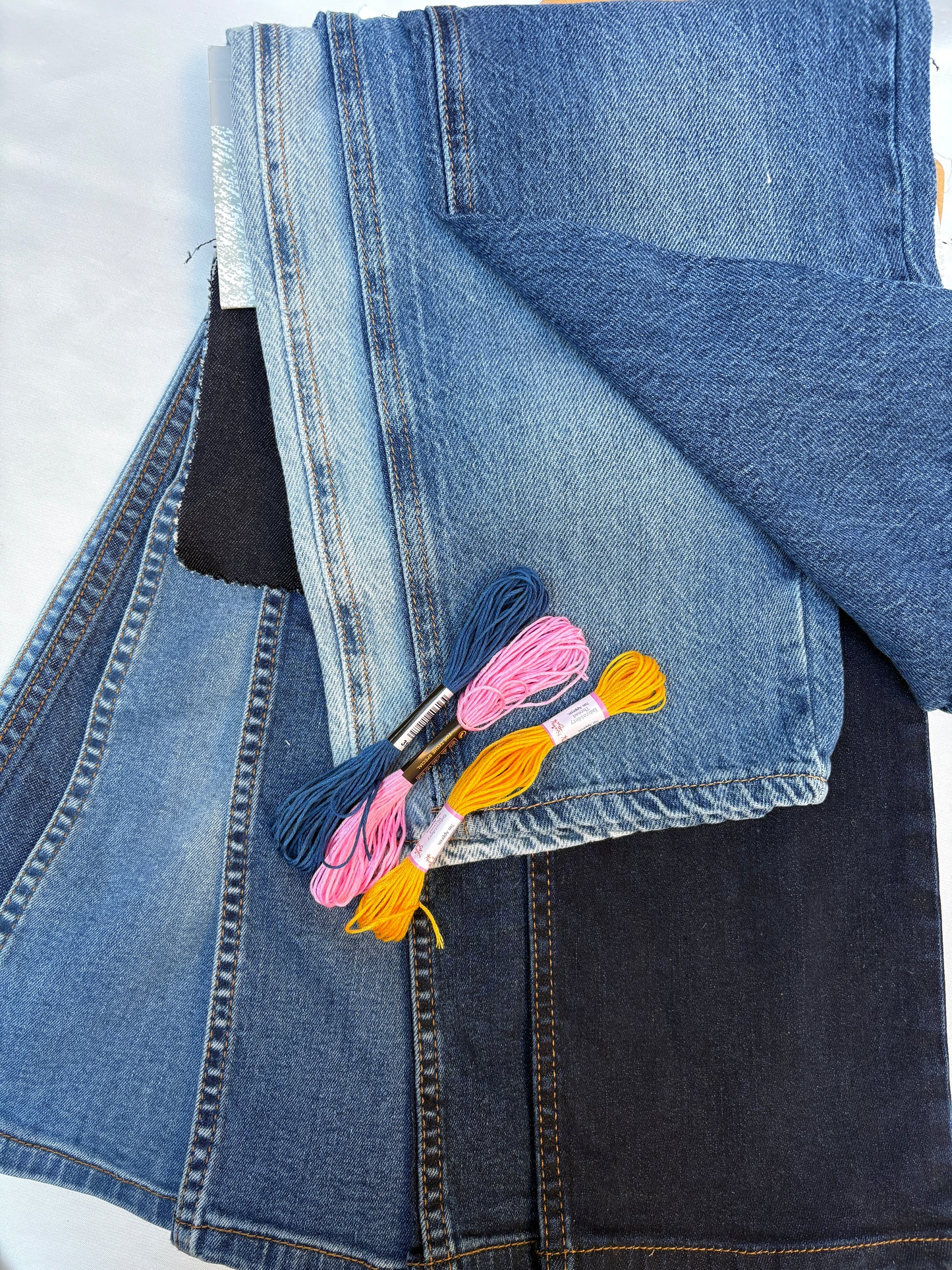 Assorted denim fabric pieces in mixed blue washes with bright embroidery threads.