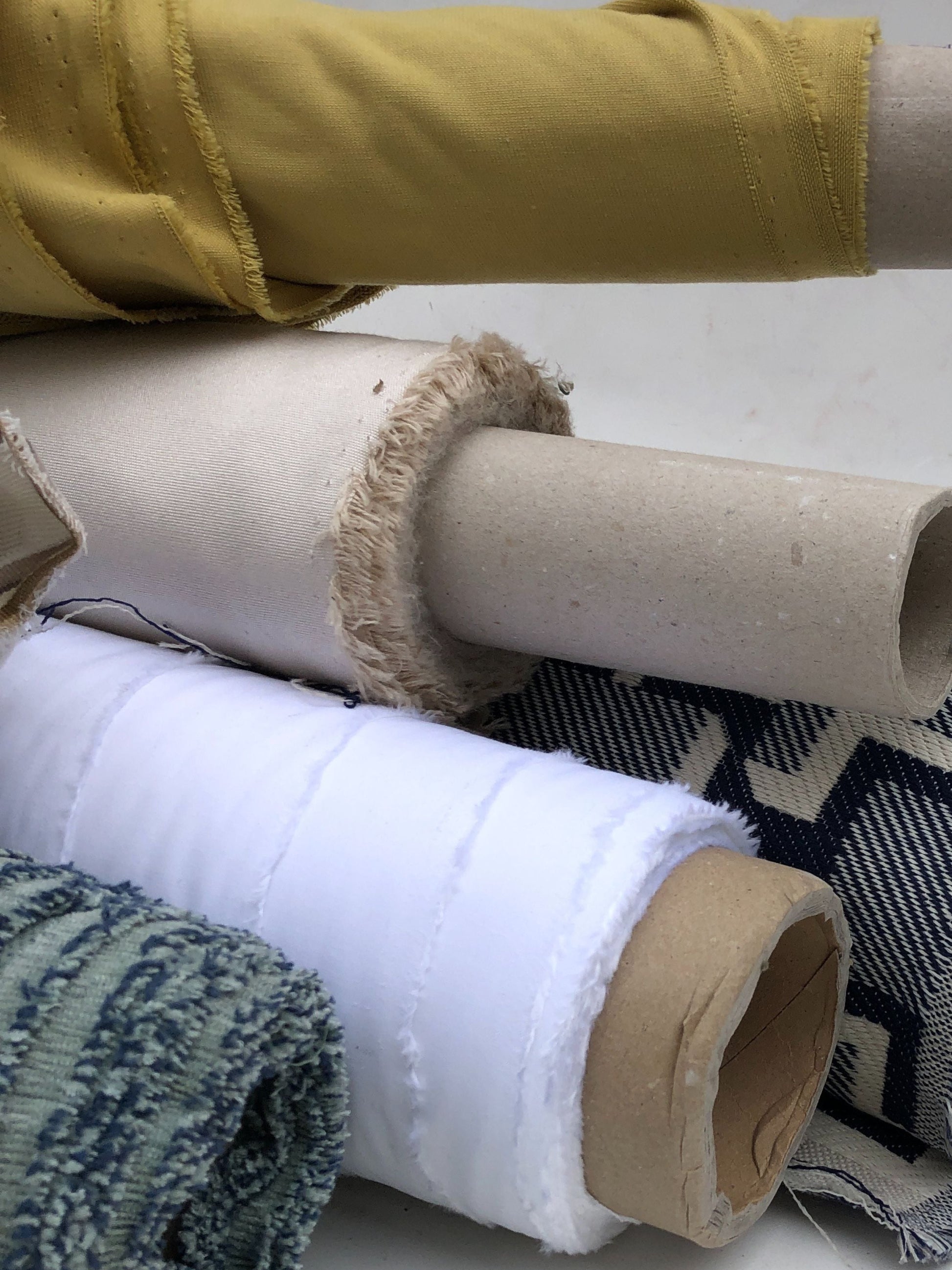Close-up of collection of various coloured, patterned, rolled fabrics, texture visible 