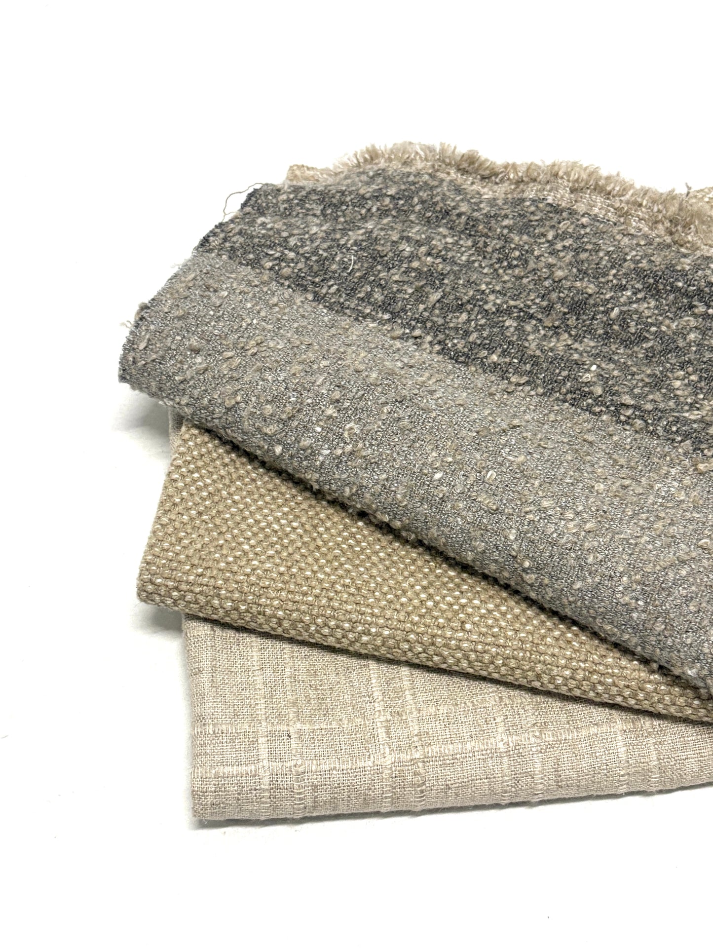 Stack of three neutral coloured heavyweight fabrics, texture visible